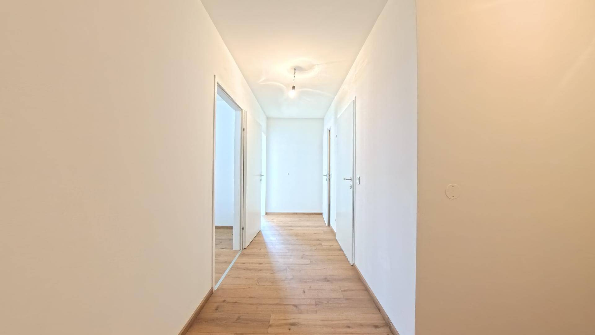 Langer, heller Flur mit Laminatboden und Türen zu angrenzenden Räumen.