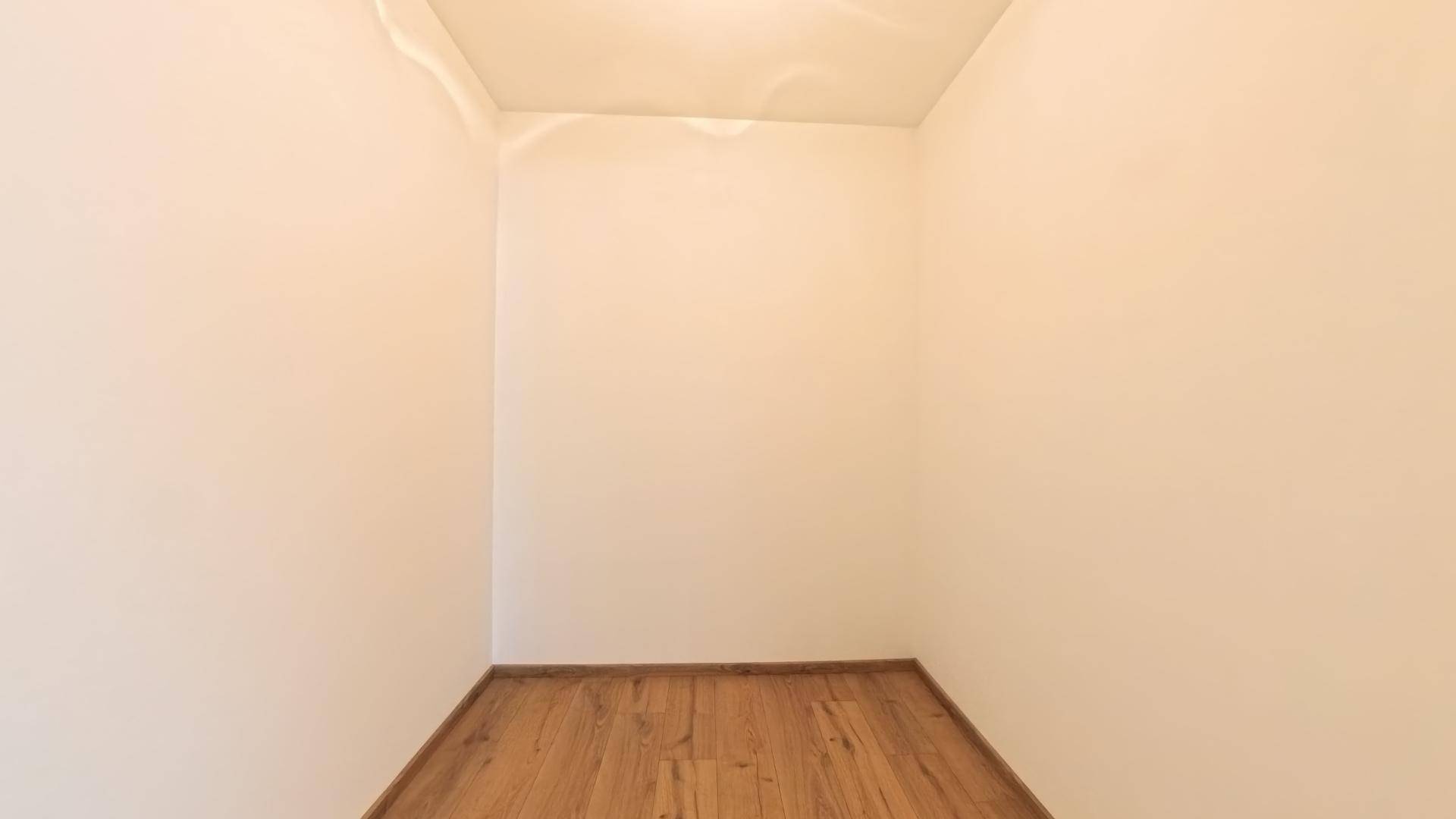 Kleiner, leerer Raum mit Laminatboden, ideal als Abstellraum oder begehbarer Kleiderschrank.