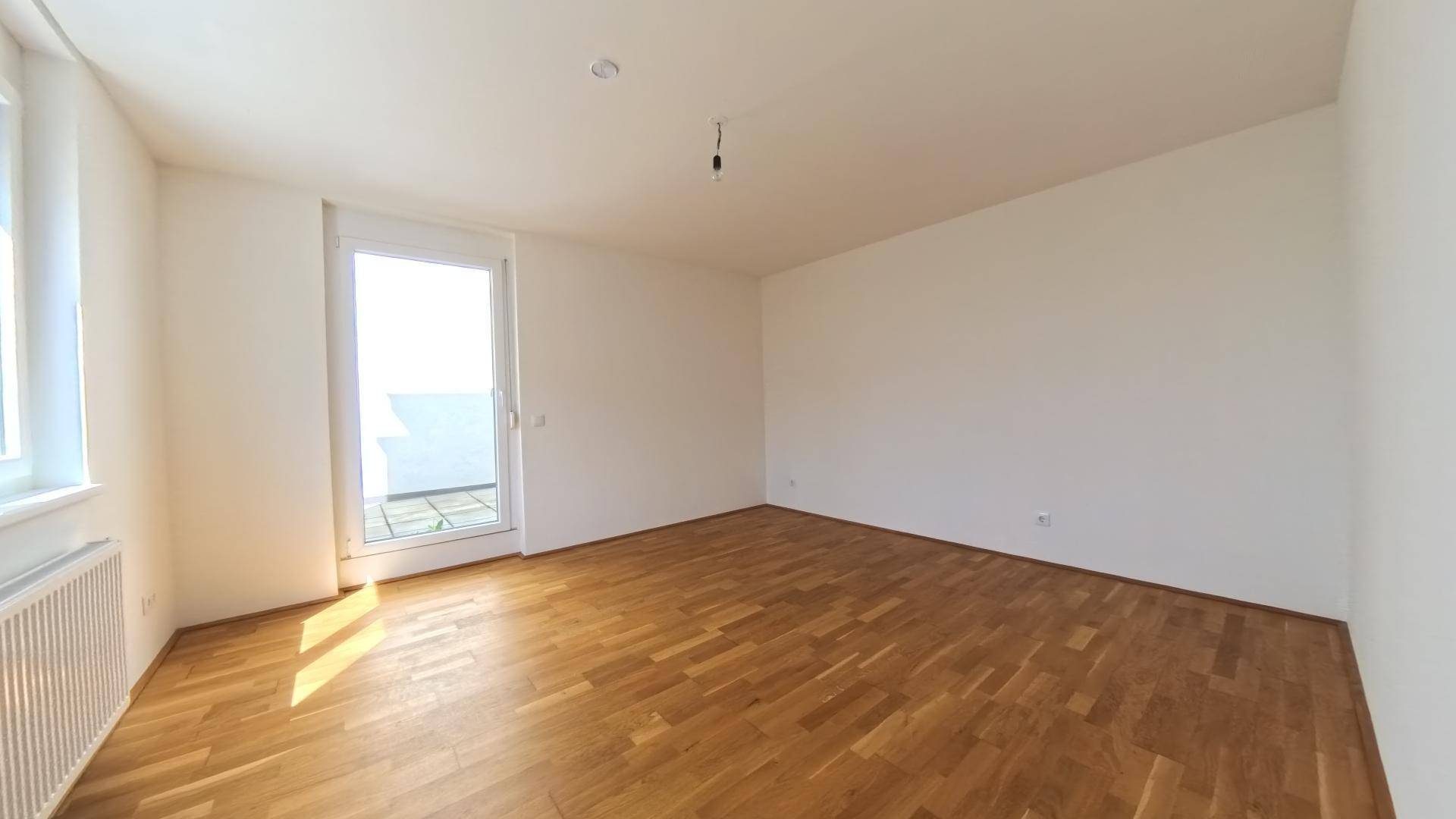 Helles Schlafzimmer mit Parkettboden und direktem Zugang zu einem Balkon oder einer Terrasse.
