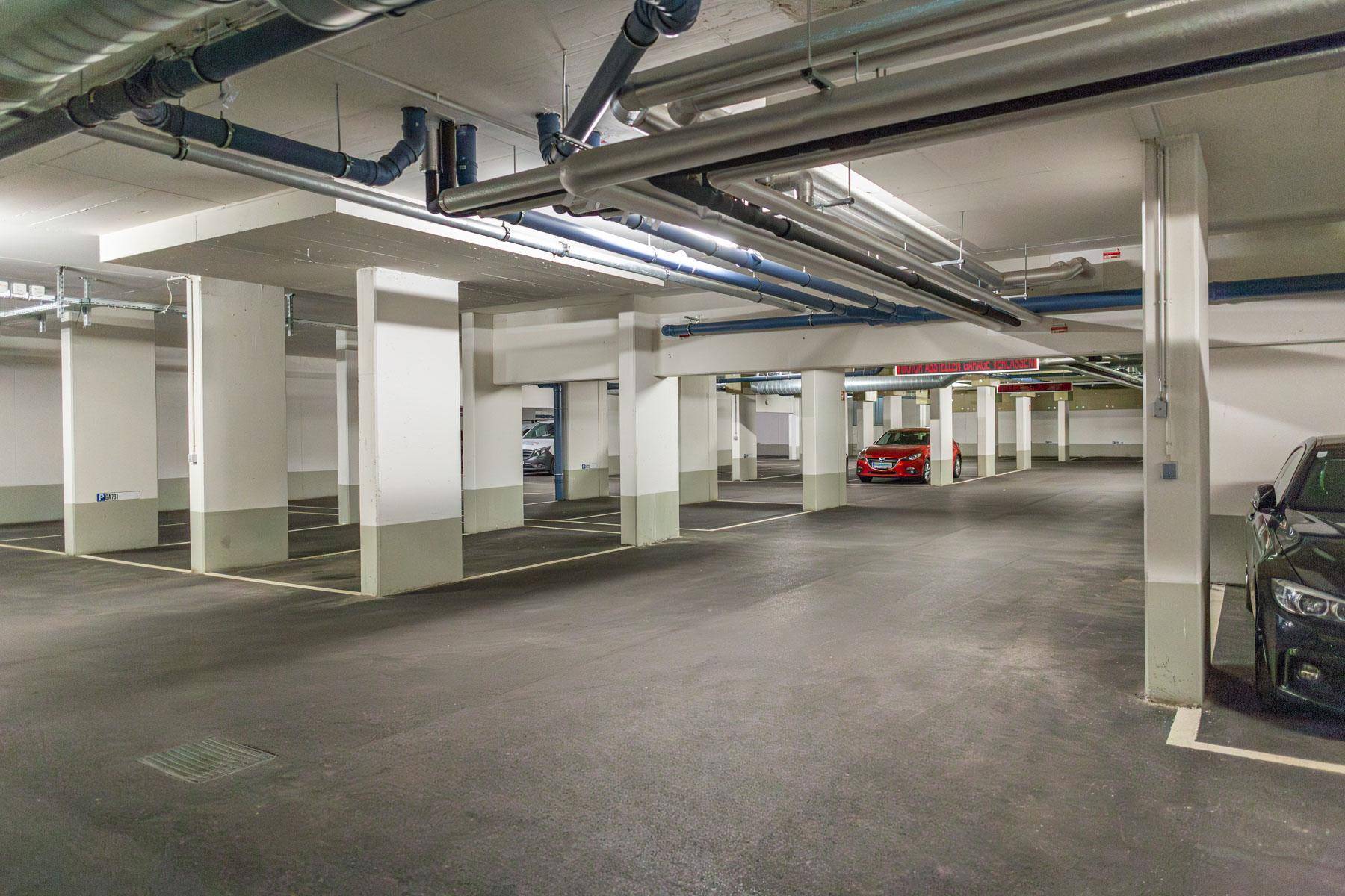 Geräumige Tiefgarage mit vielen Stellplätzen, Betonpfeilern und sichtbaren Installationen.