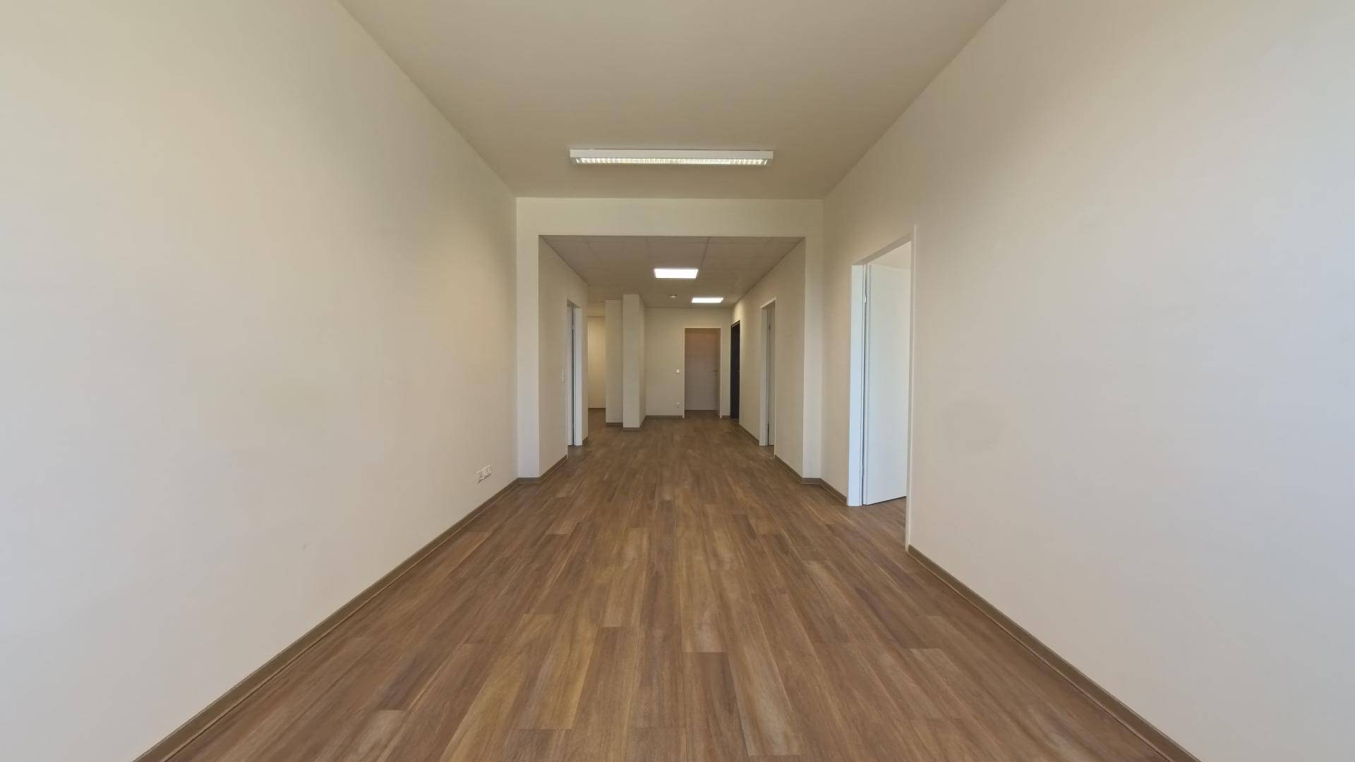 Langer, heller Flur mit Laminatboden und mehreren Türen, der zu weiteren Räumen führt.