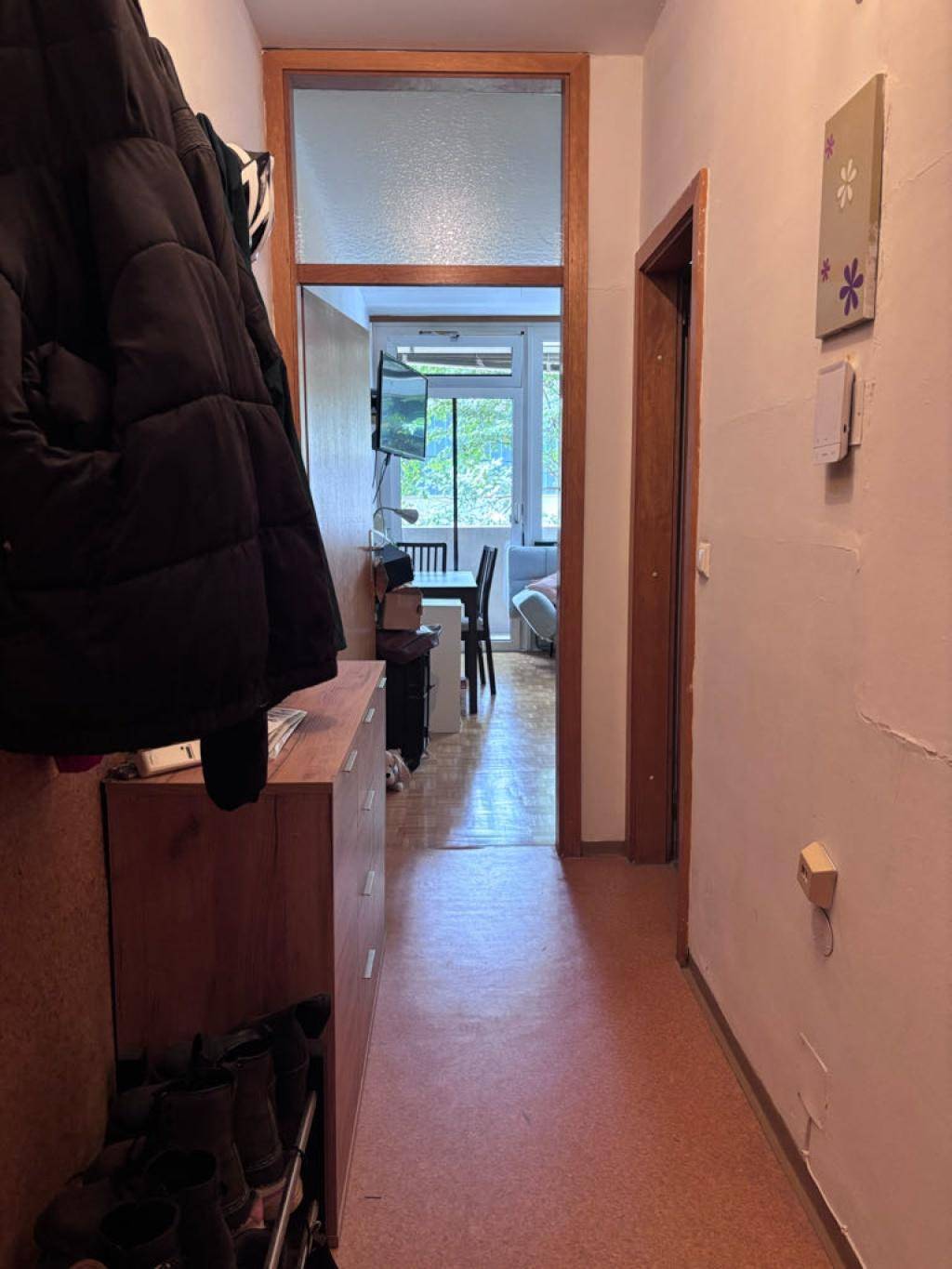 Flur mit Garderobe und Blick in einen hellen Raum mit Balkonzugang.