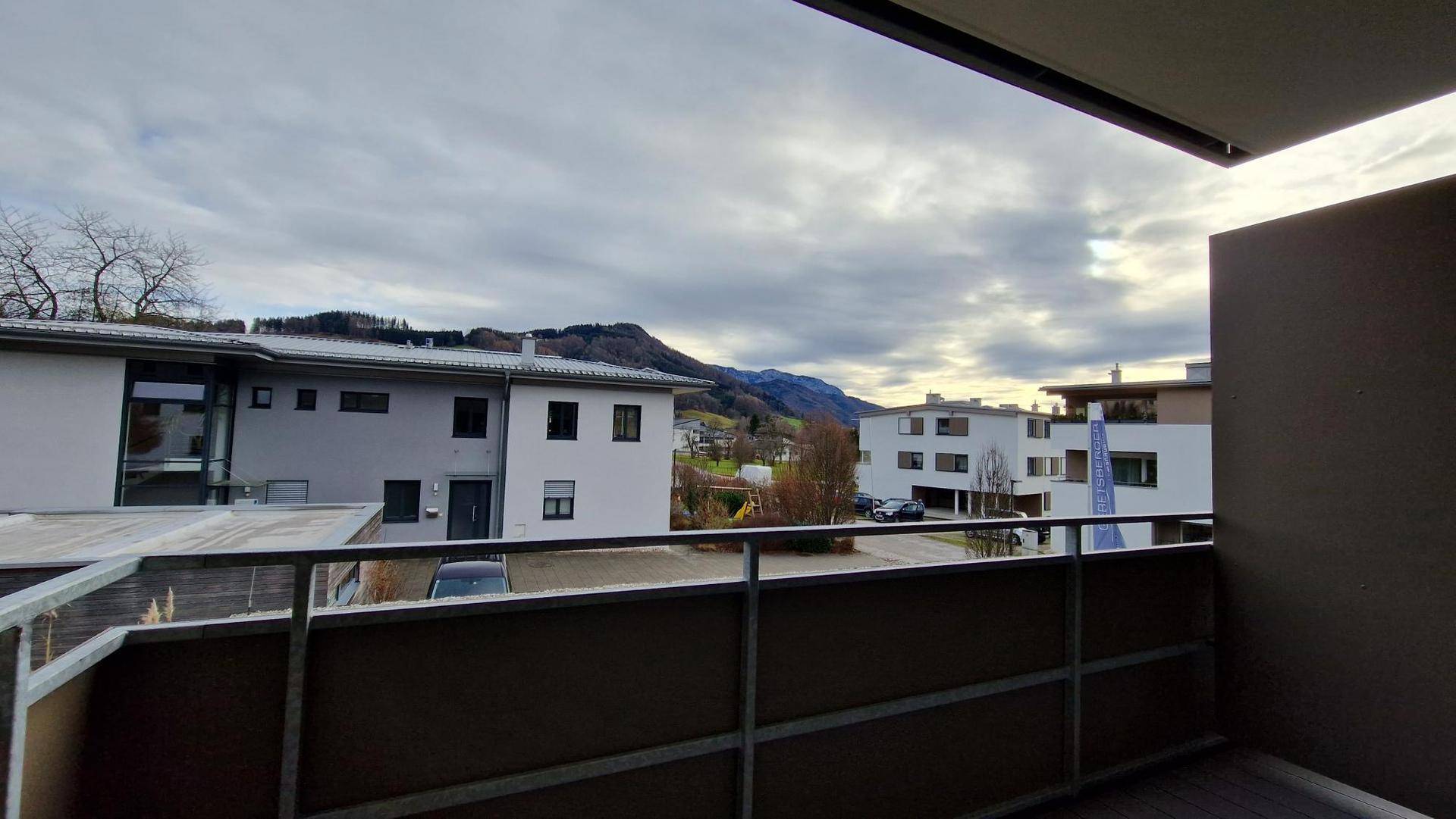 Balkon mit weitem Blick auf die umliegende Berglandschaft und benachbarte Gebäude.
