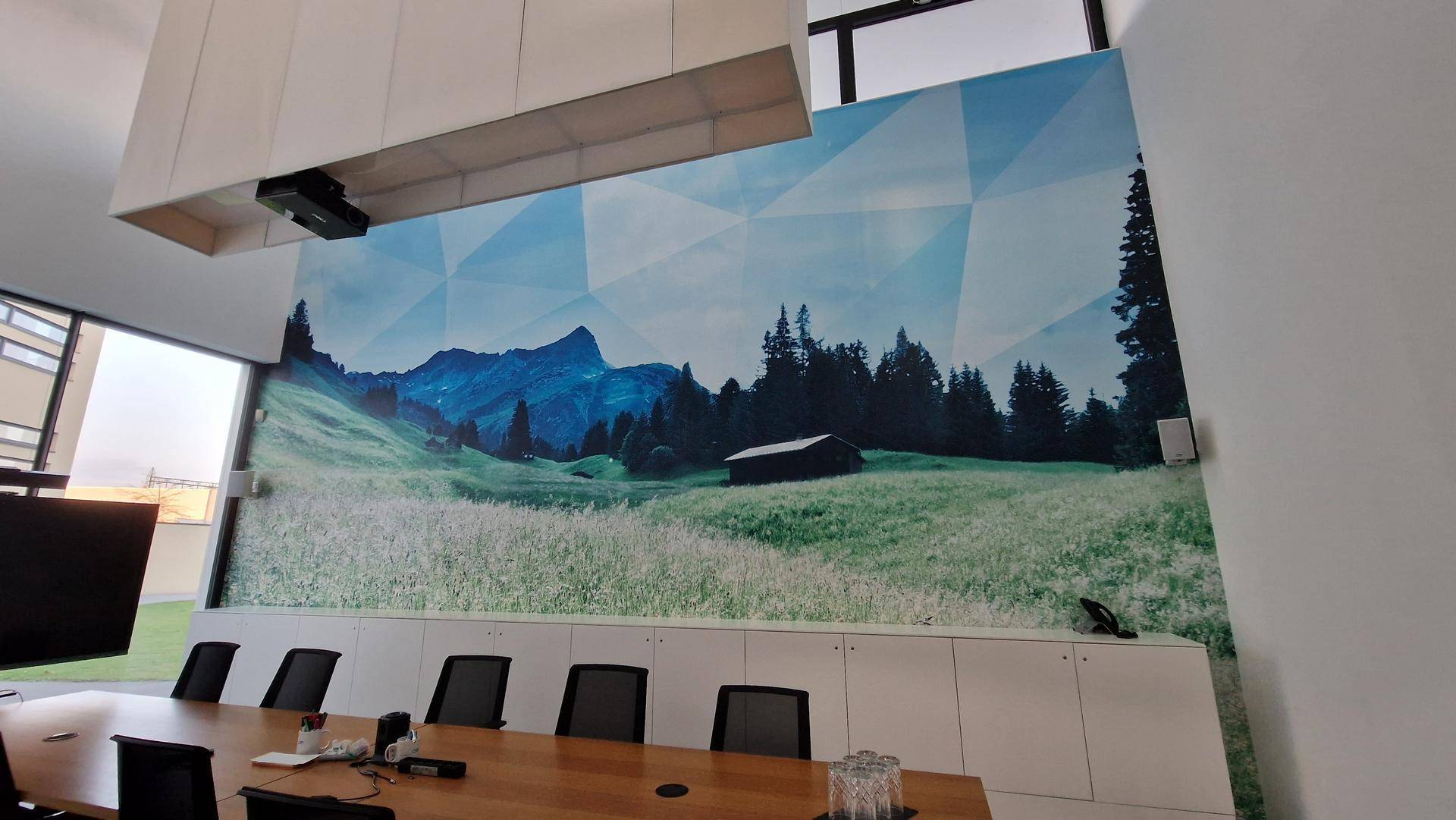 Besprechungsraum mit einem großen Wandbild, das eine malerische Berglandschaft darstellt.