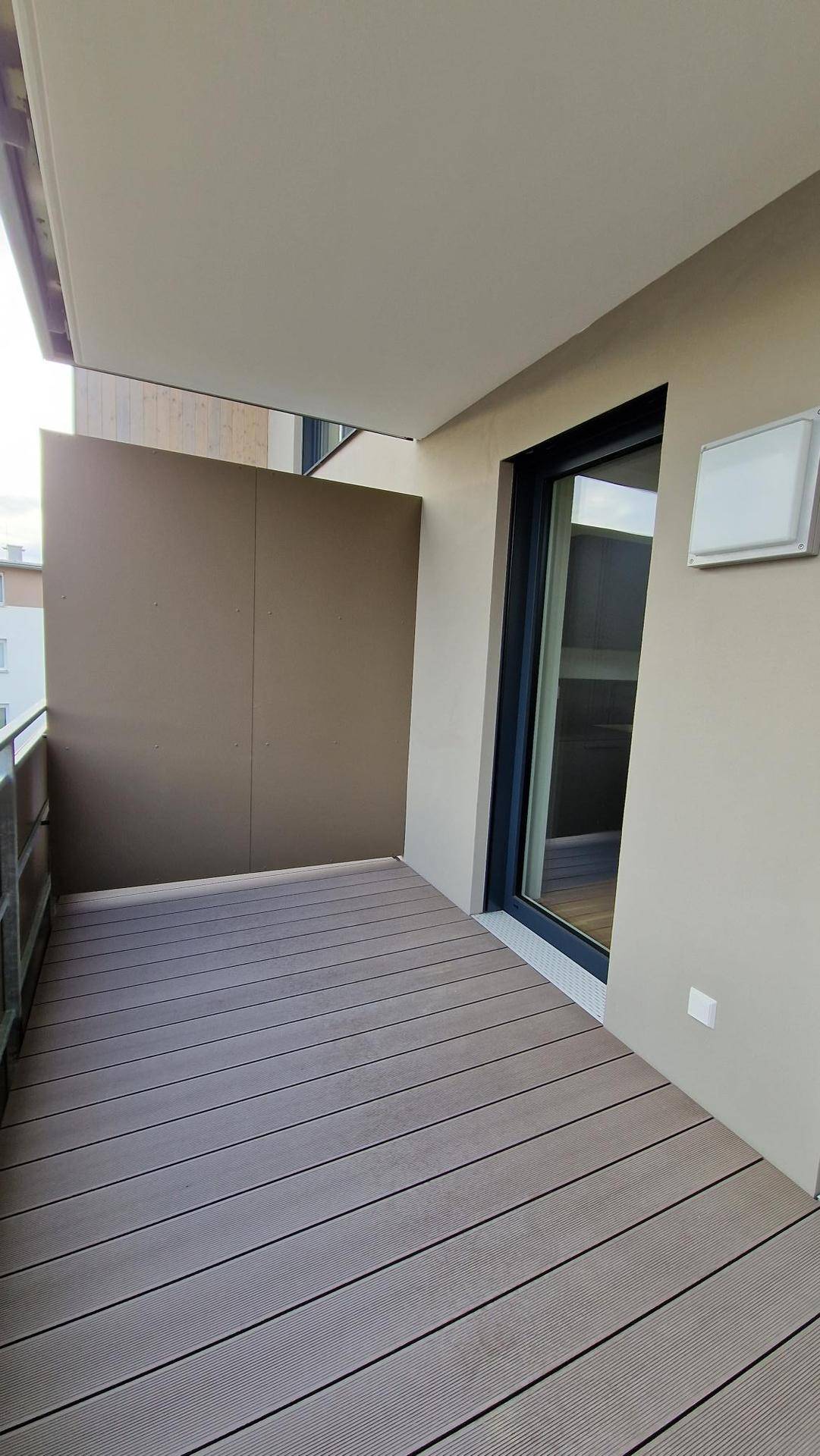 Balkon mit Holzdielenboden und seitlichem Sichtschutz, bietet einen privaten Außenbereich.