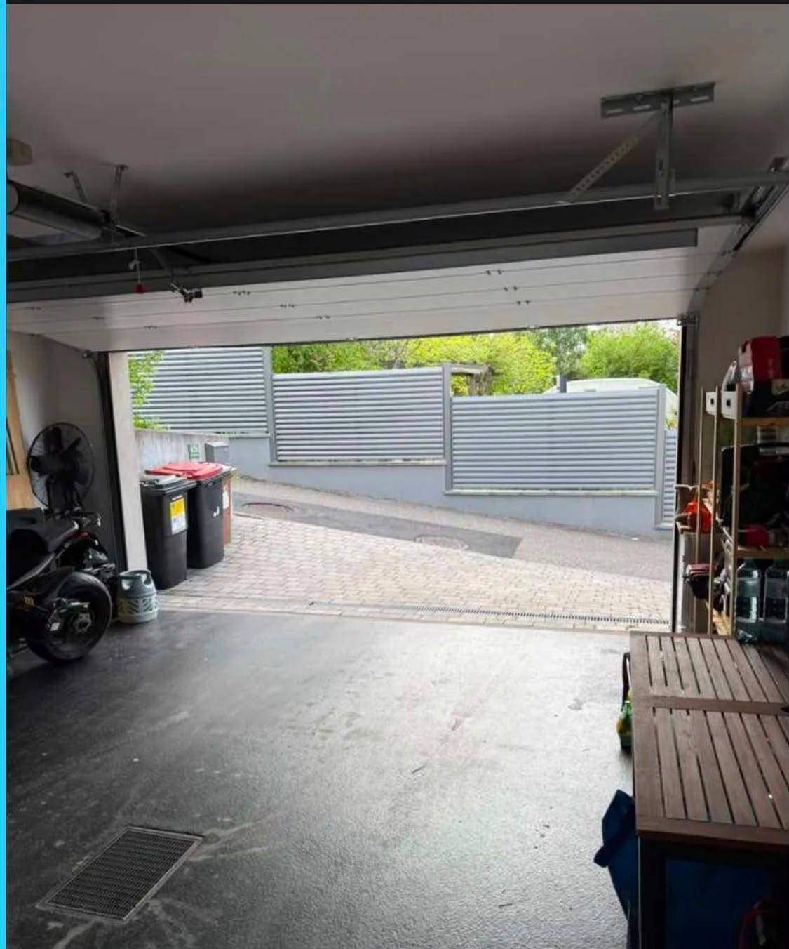 Geräumige Garage mit offenem Tor und Blick auf die gepflasterte Zufahrt.