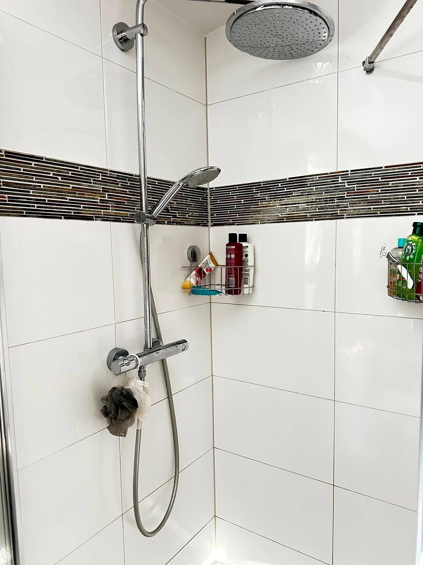 Moderne Dusche mit Regenduschkopf und weißen Fliesen im Badezimmer.