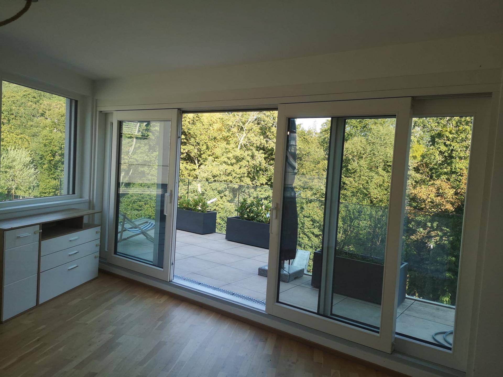 Heller Innenraum mit großen Schiebetüren, die auf die Terrasse führen und Blick ins Grüne bieten.