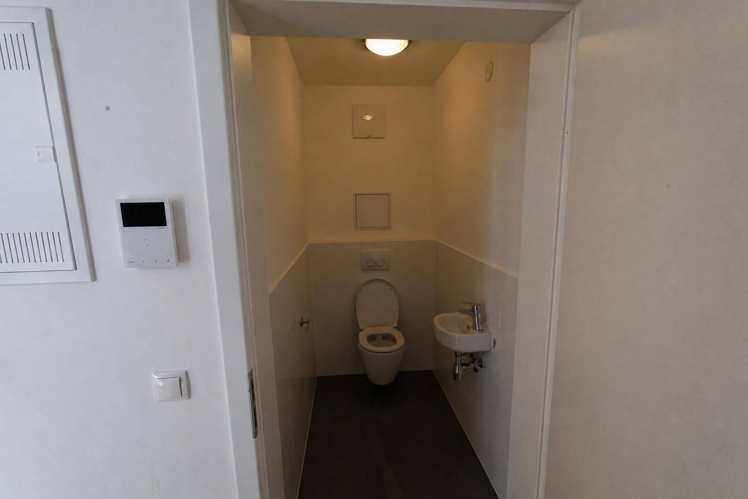 Kleines Gäste-WC mit wandhängender Toilette und Handwaschbecken.
