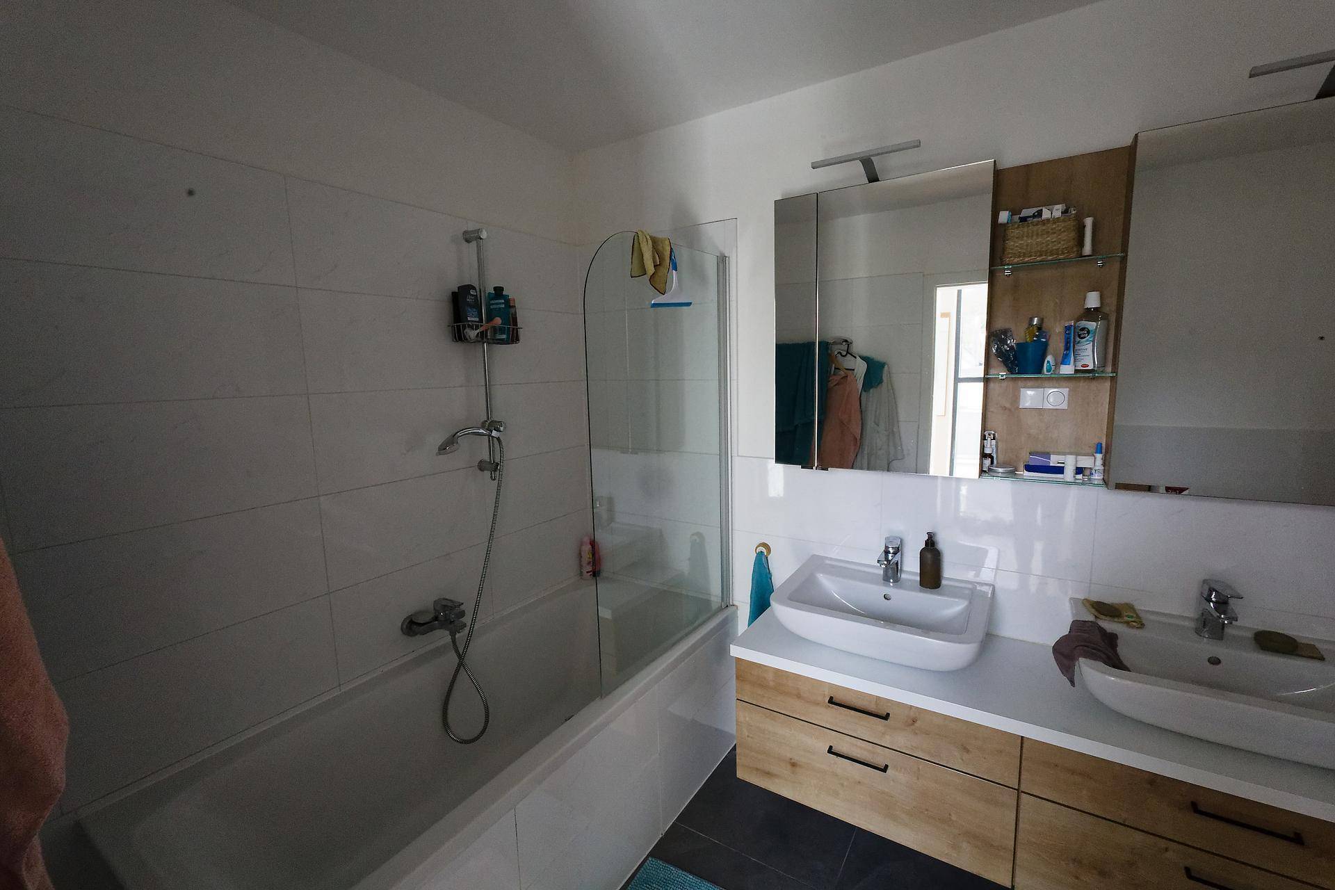 Modernes Badezimmer mit Badewanne, Doppelwaschbecken und Spiegelschrank.