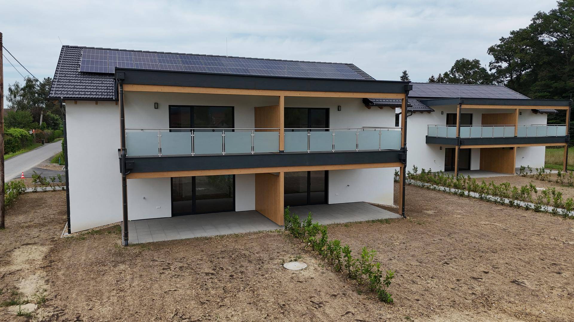 Luftaufnahme von zwei modernen Doppelhaushälften mit Balkonen und Solaranlagen.