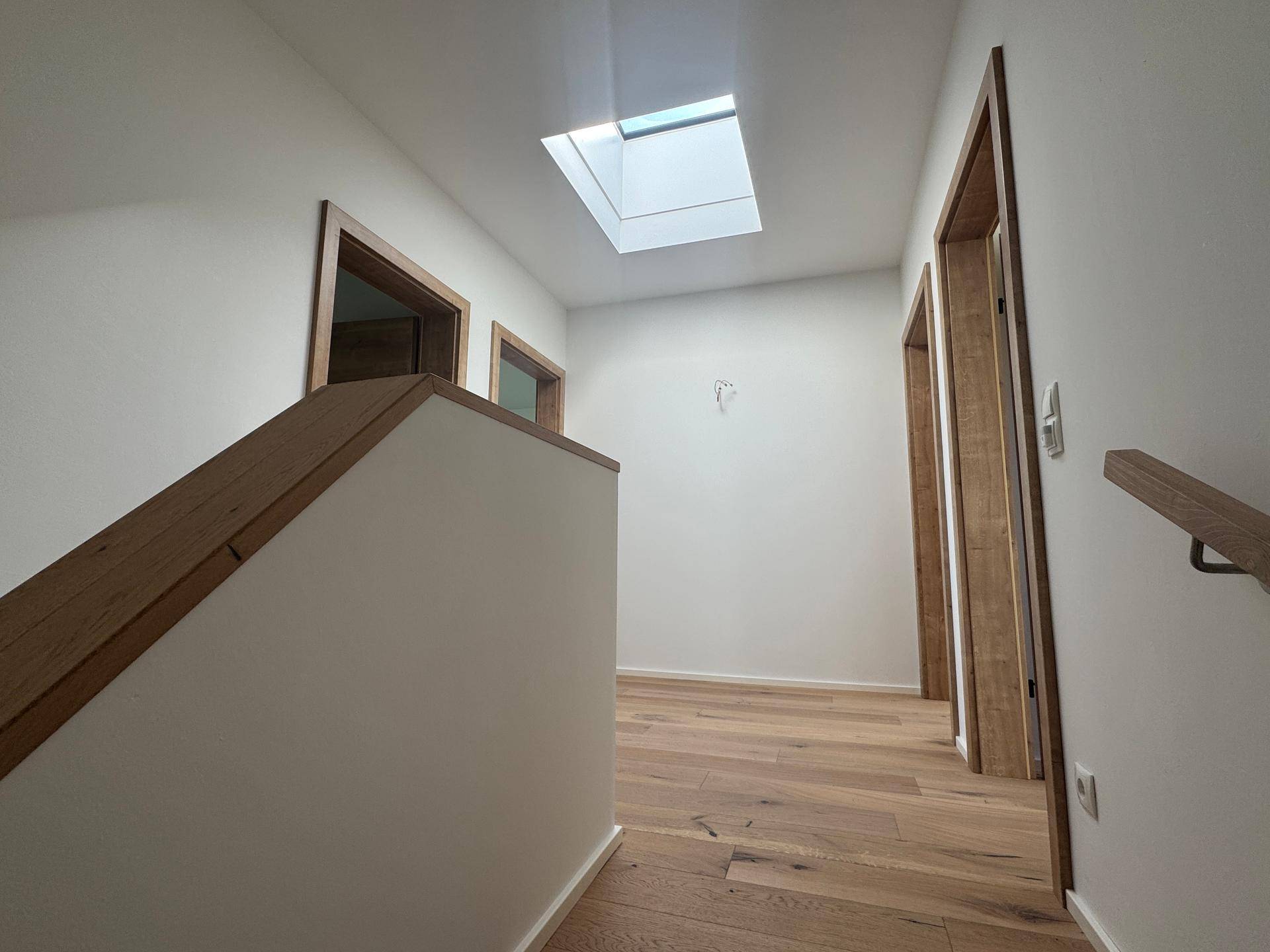 Heller Flur im Obergeschoss mit Eichenparkett, Holztüren und Oberlicht.