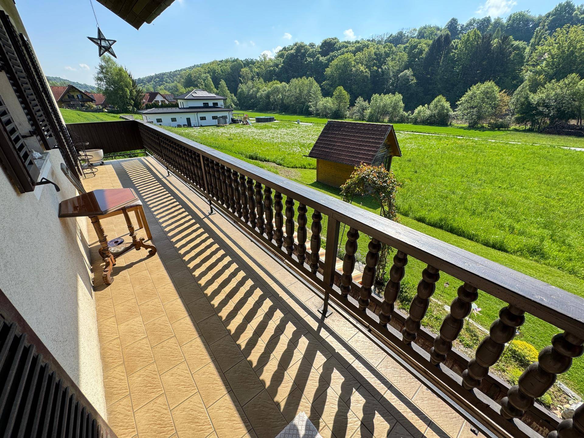 Geräumiger Balkon mit Fliesenboden und traditionellem Holzgeländer, bietet weite Aussicht.