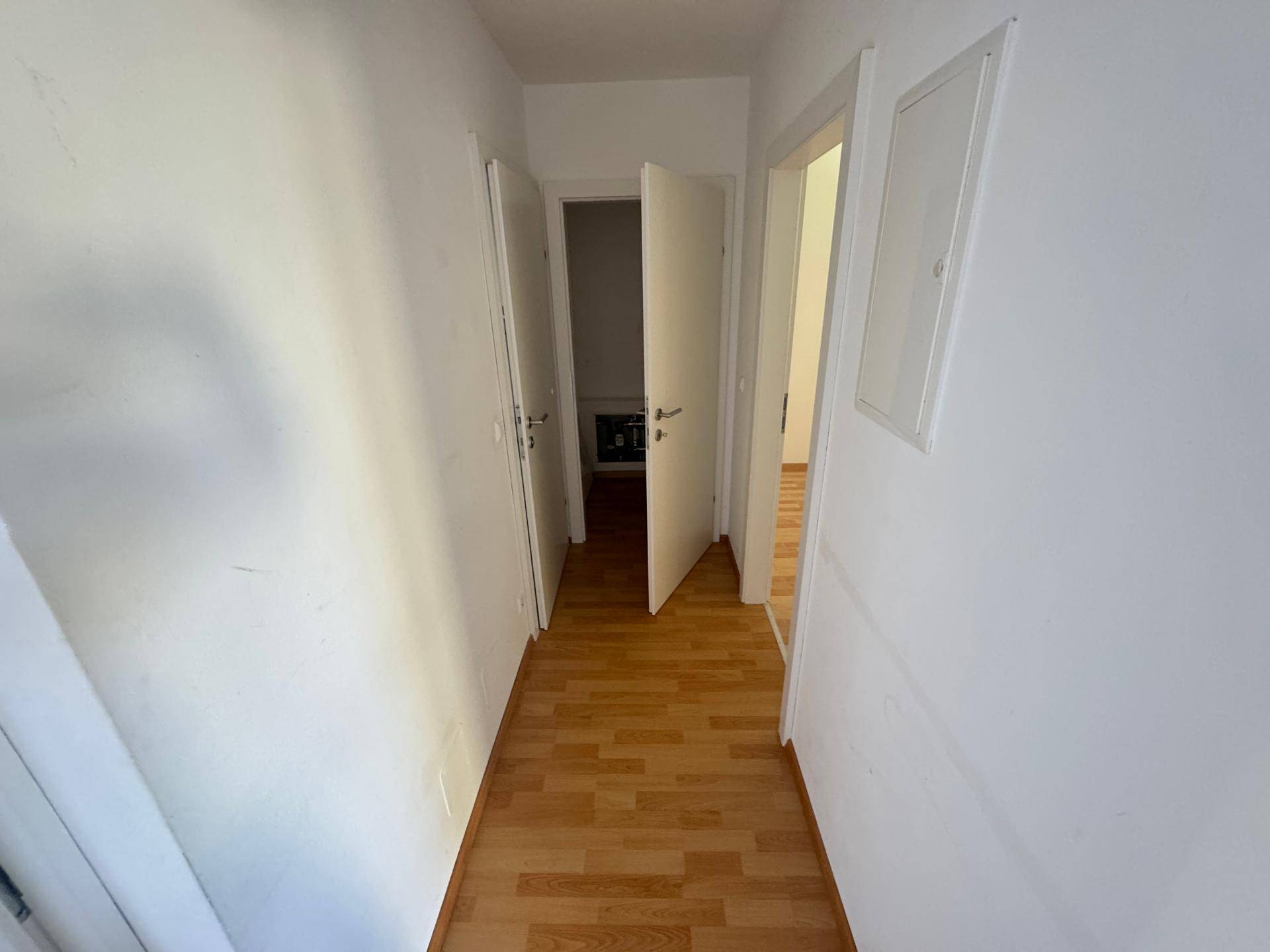 Heller Flur mit Laminatboden und mehreren Türen, die zu den angrenzenden Räumen führen.