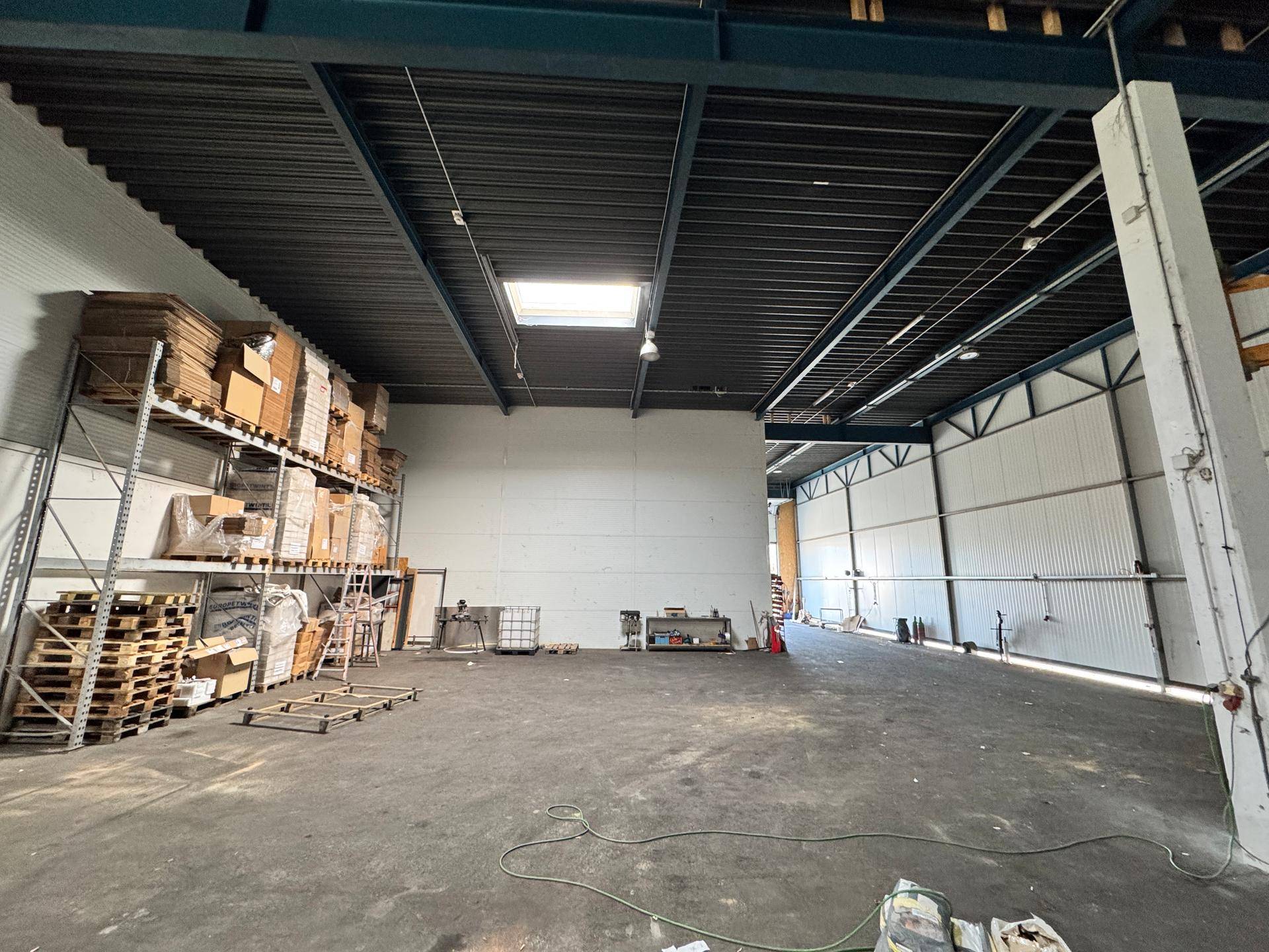 Geräumige Lagerhalle mit hohen Decken, Oberlicht und Regalen voller Kartons.