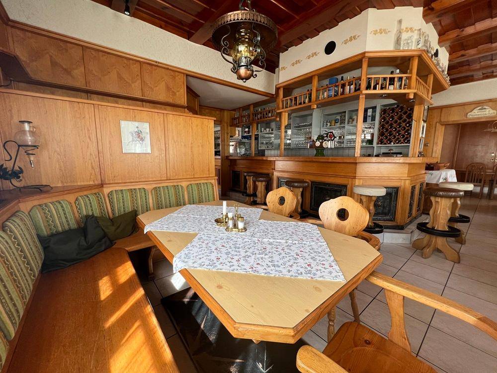 Traditioneller Essbereich mit Holzbänken und Blick auf die rustikale Bar.