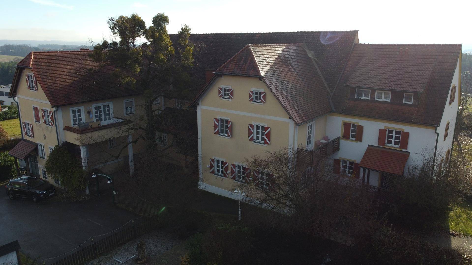 Luftaufnahme des Gebäudekomplexes mit traditionellen Dächern und umliegender Landschaft.