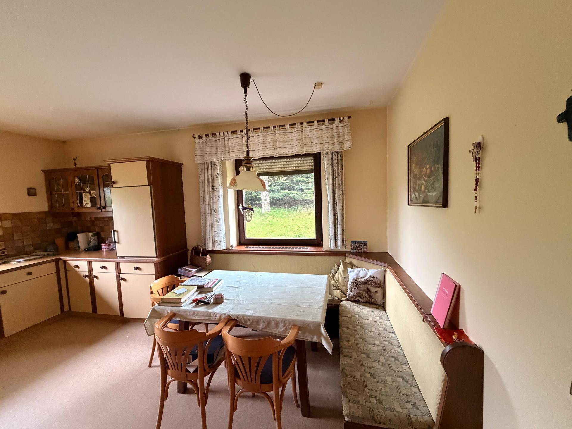 Traditionelle Küche mit Essbereich, Holzmöbeln und Fenster zum Garten.
