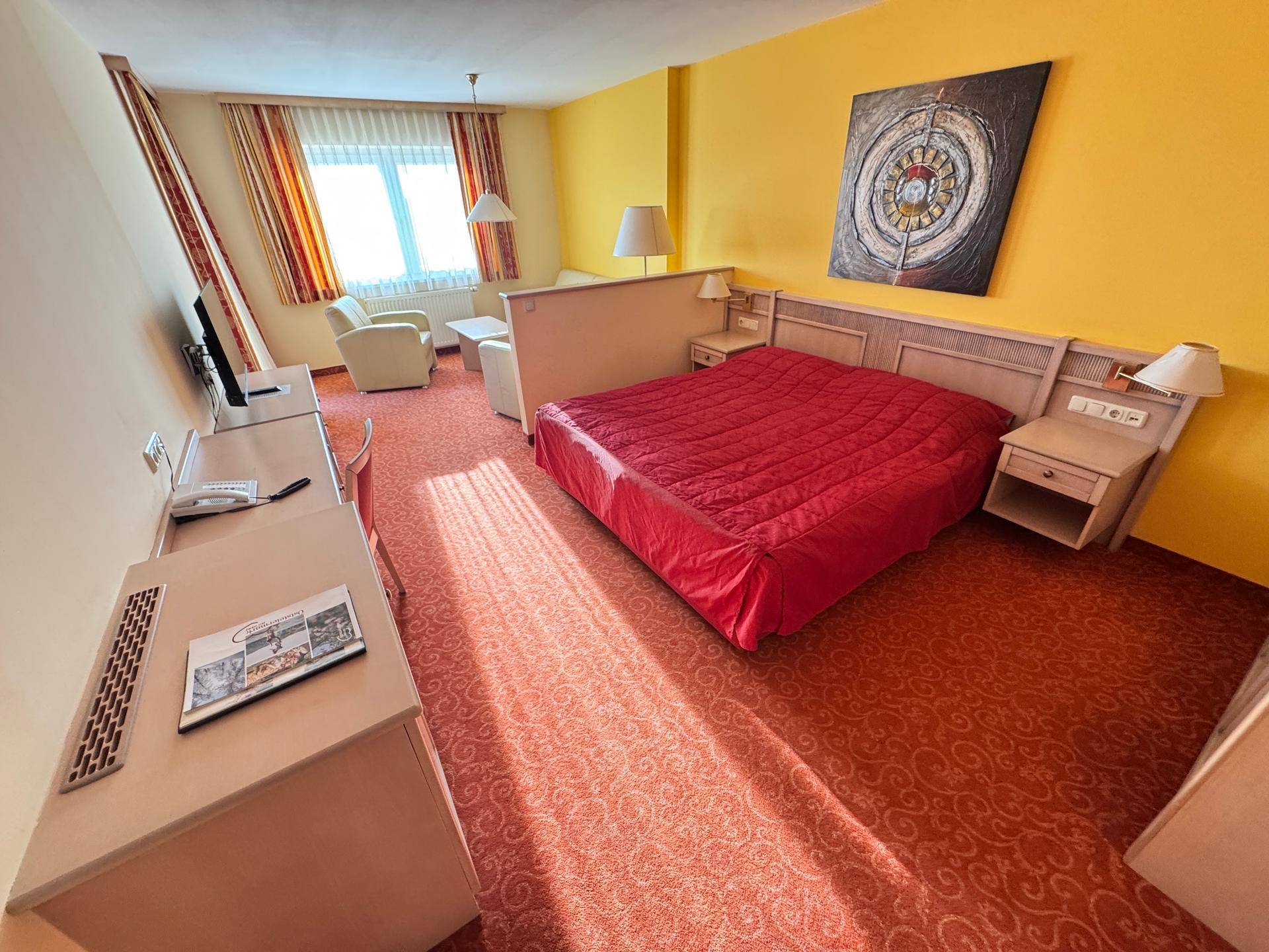 Schlafzimmer mit Doppelbett, Sitzbereich und Teppichboden.
