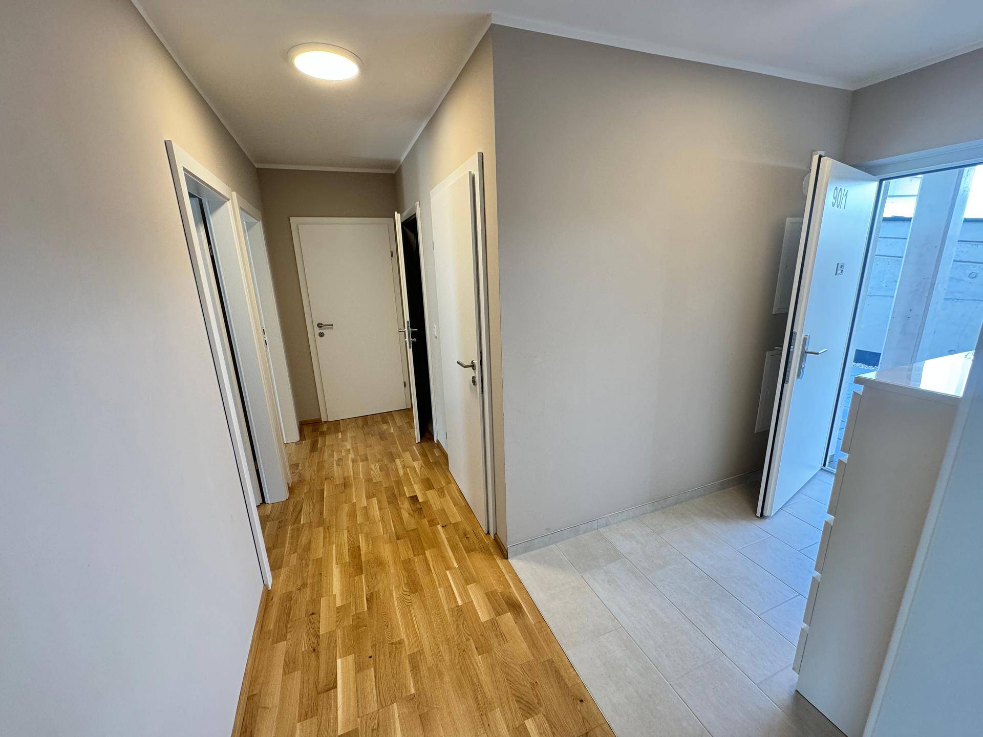 Heller Flur mit Holzboden und mehreren Türen zu den angrenzenden Räumen der Wohnung.
