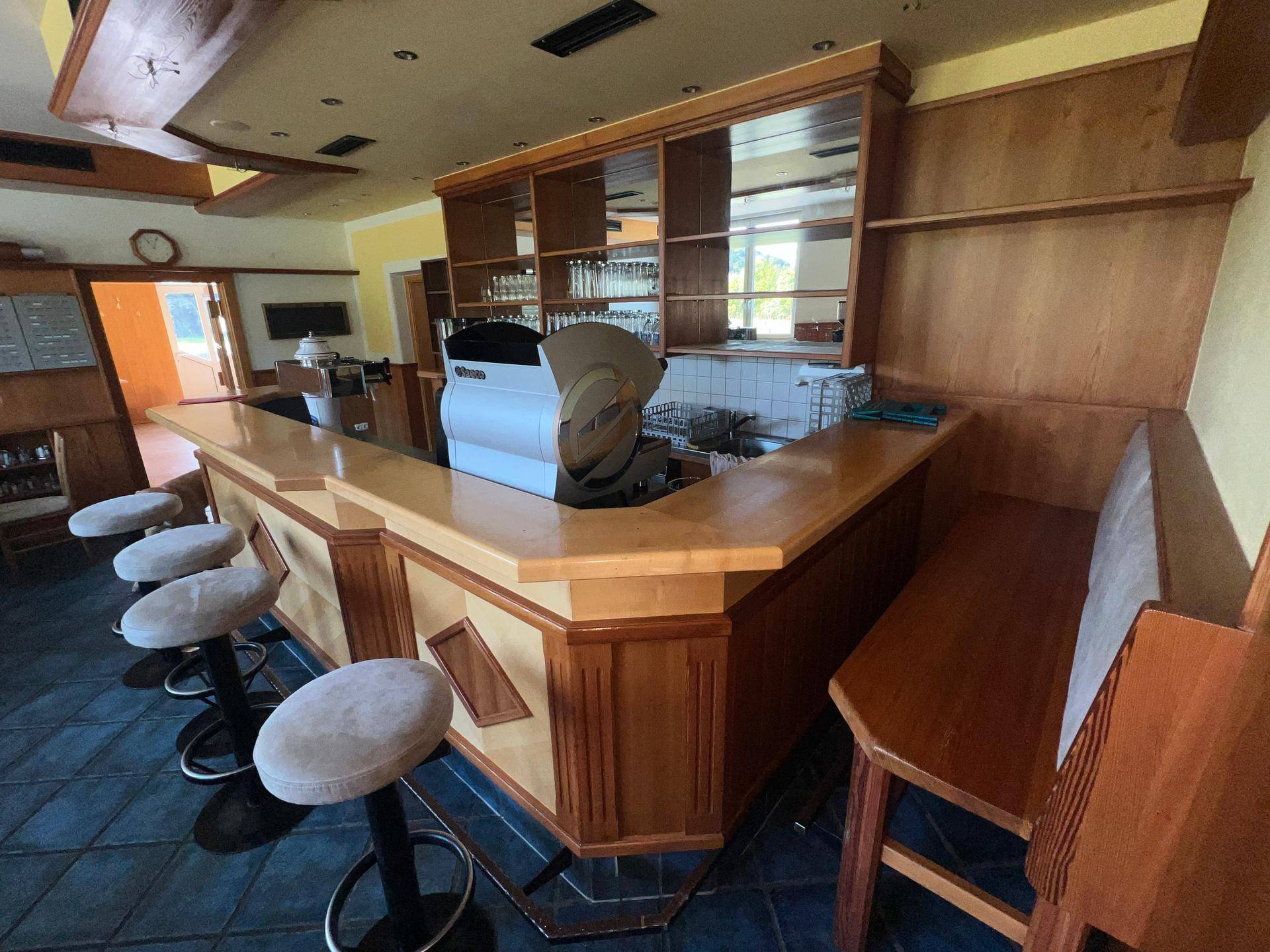 Gut ausgestattete Bar mit Theke, Barhockern und integrierten Regalen, ideal für Gastronomie.