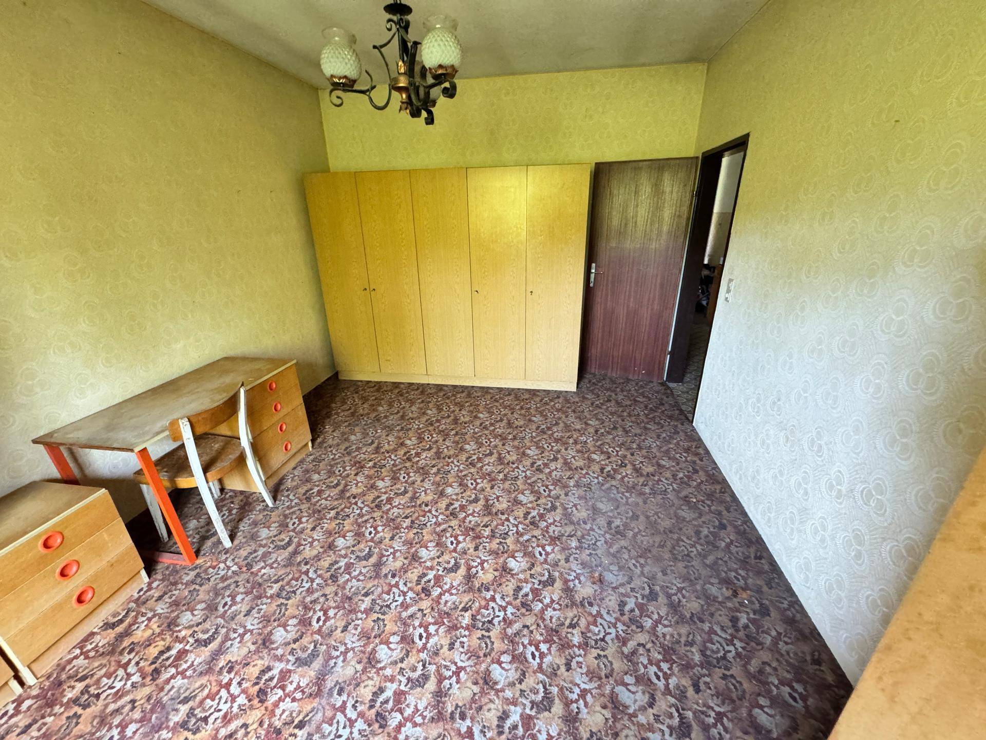 Schlafzimmer mit gemustertem Boden, Kleiderschränken und Schreibtisch.