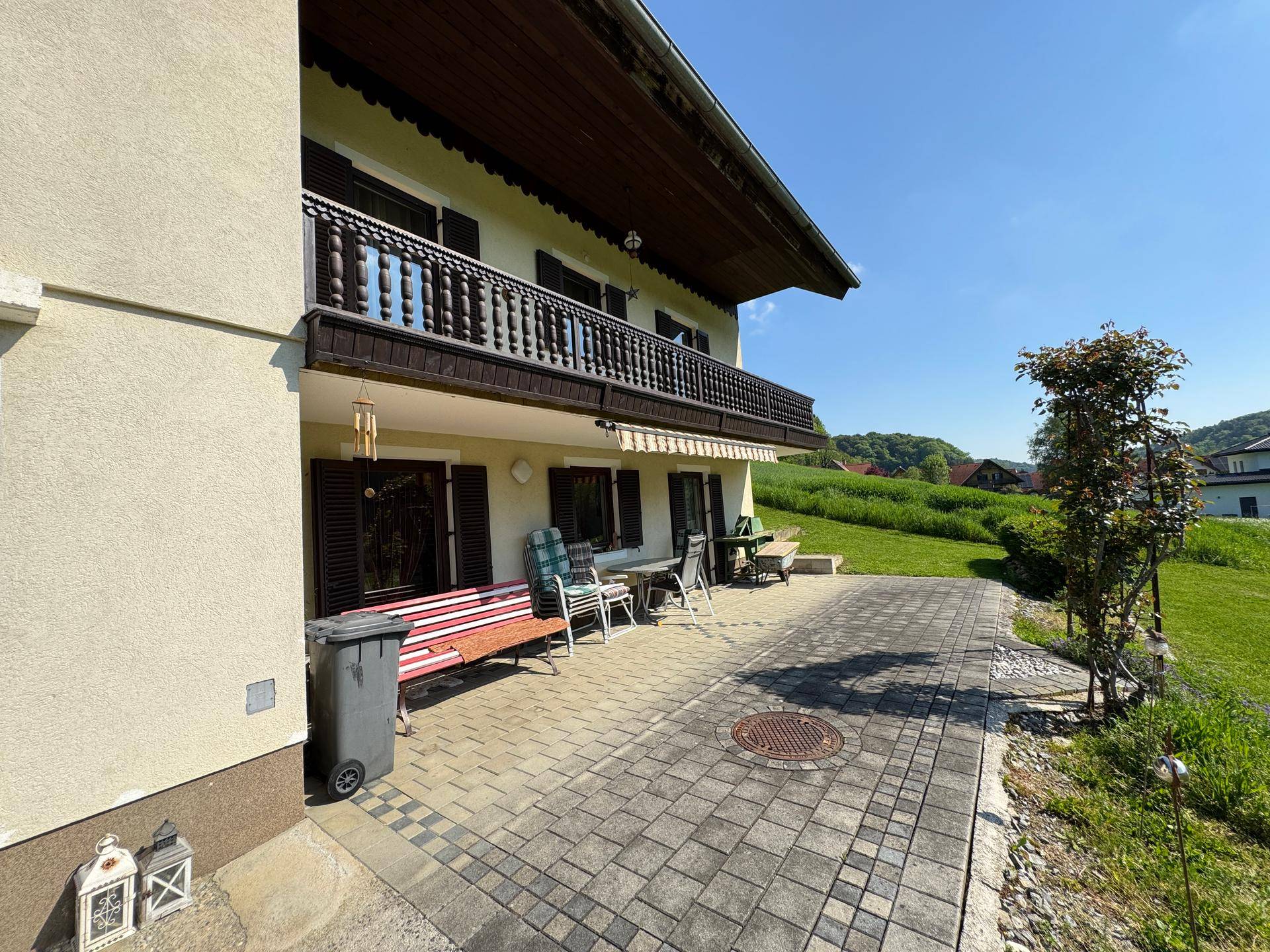 Gepflasterte Terrasse am Haus mit Sitzgelegenheiten und Zugang zum grünen Garten.