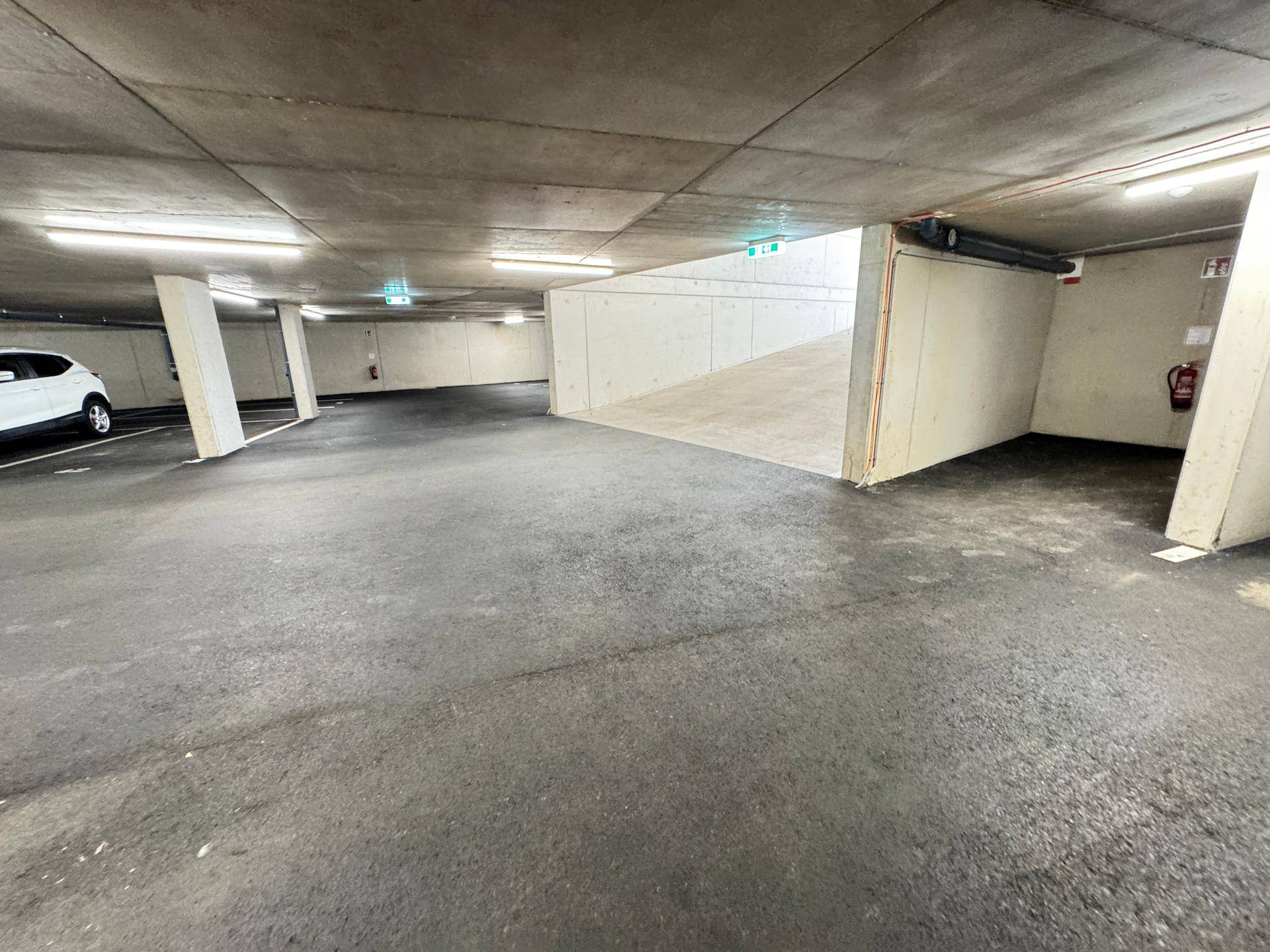 Geräumige Tiefgarage mit Betonwänden und -decken, bietet mehrere Stellplätze.