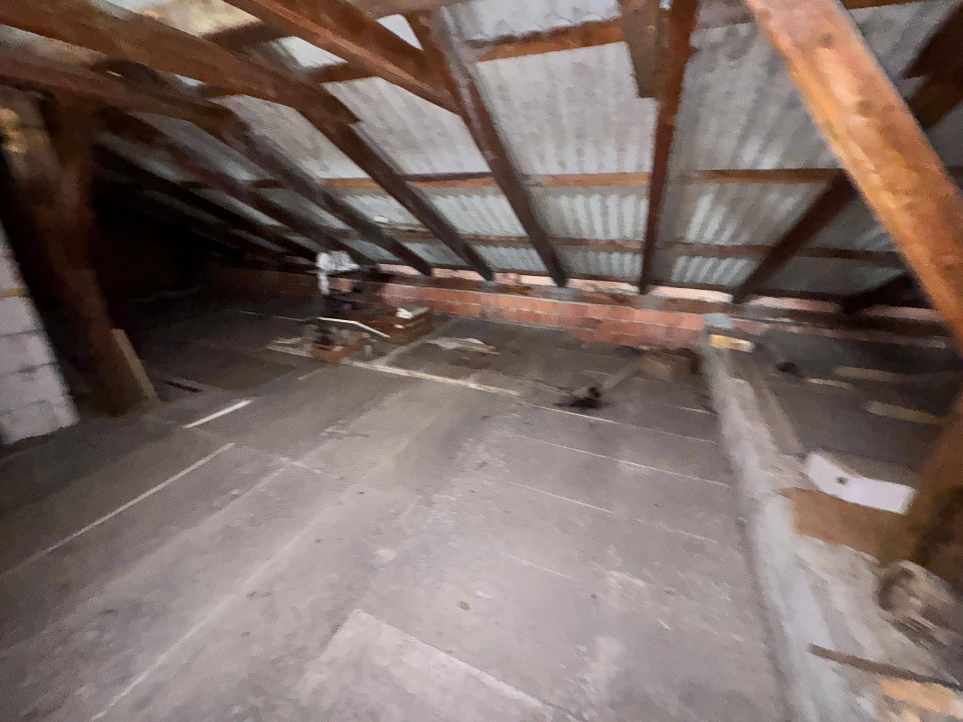 Unausgebauter Dachboden mit sichtbaren Holzbalken und Wellblechdachkonstruktion, bereit zum Ausbau.