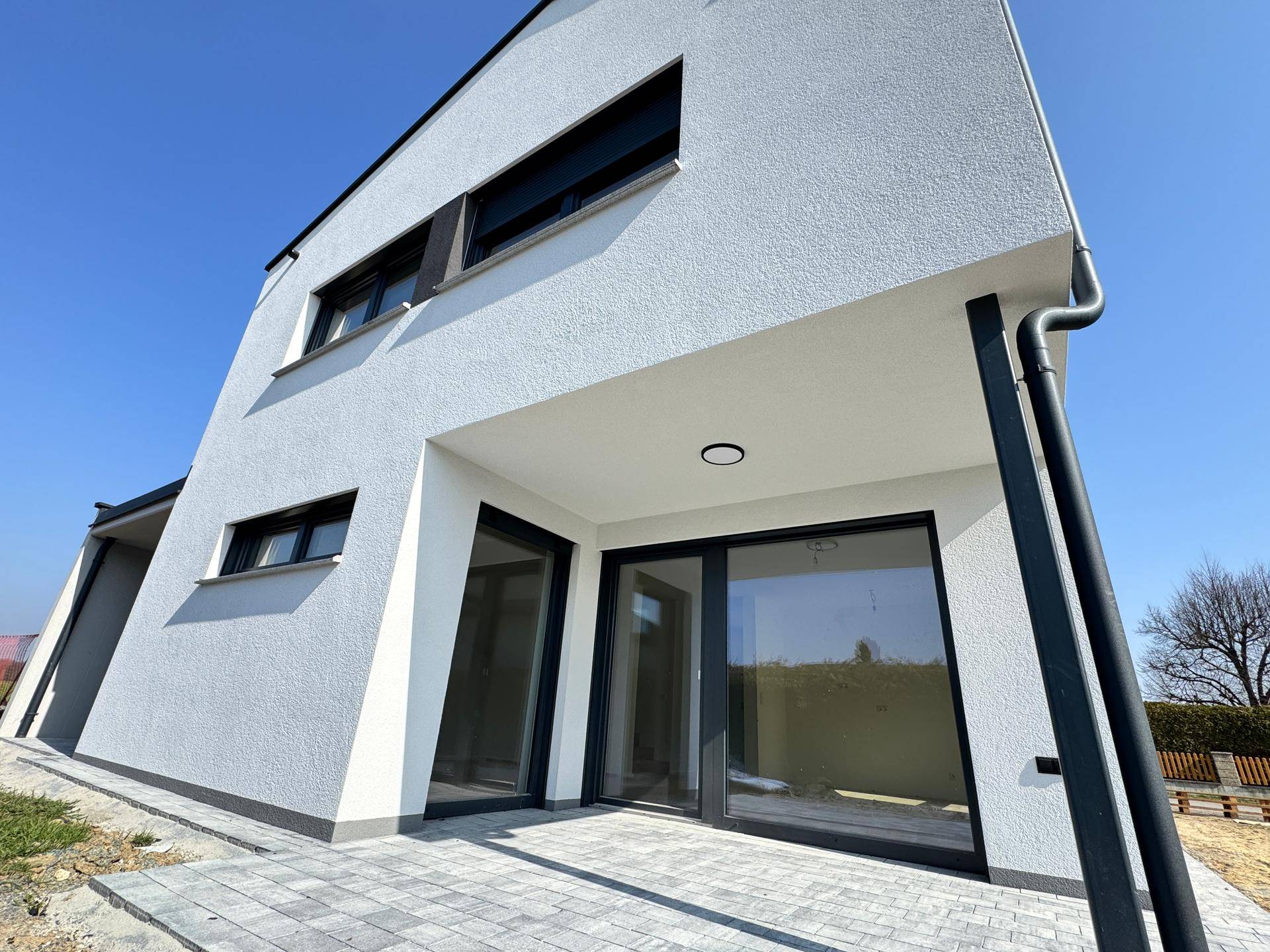 Überdachter Terrassenbereich mit großen Glasfronten und Blick auf den zukünftigen Garten.