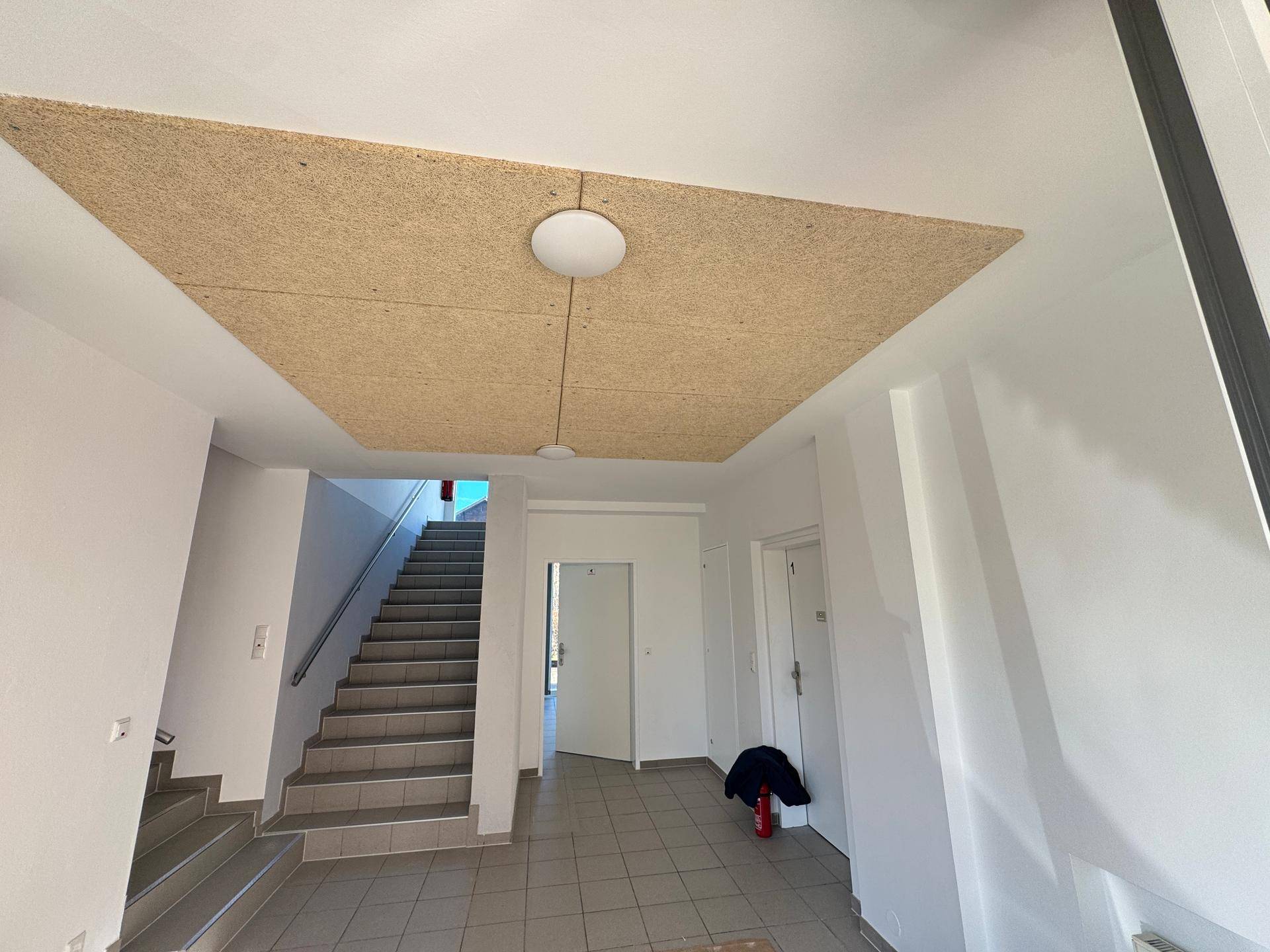 Heller Eingangsbereich mit Treppenaufgang und dekorativer Deckenverkleidung.