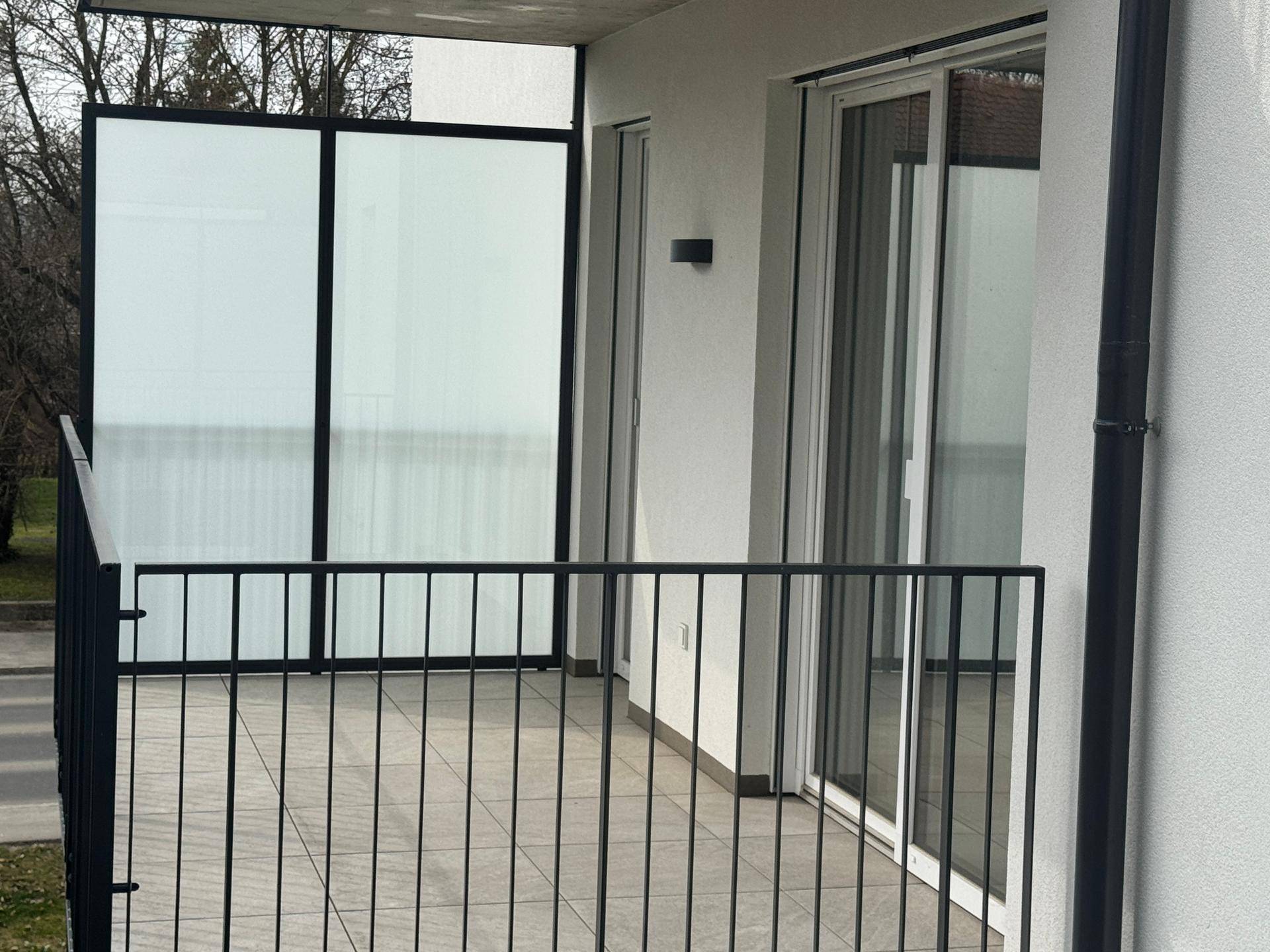 Balkon mit Fliesenboden und Blick auf die Straße und angrenzende Gebäude.