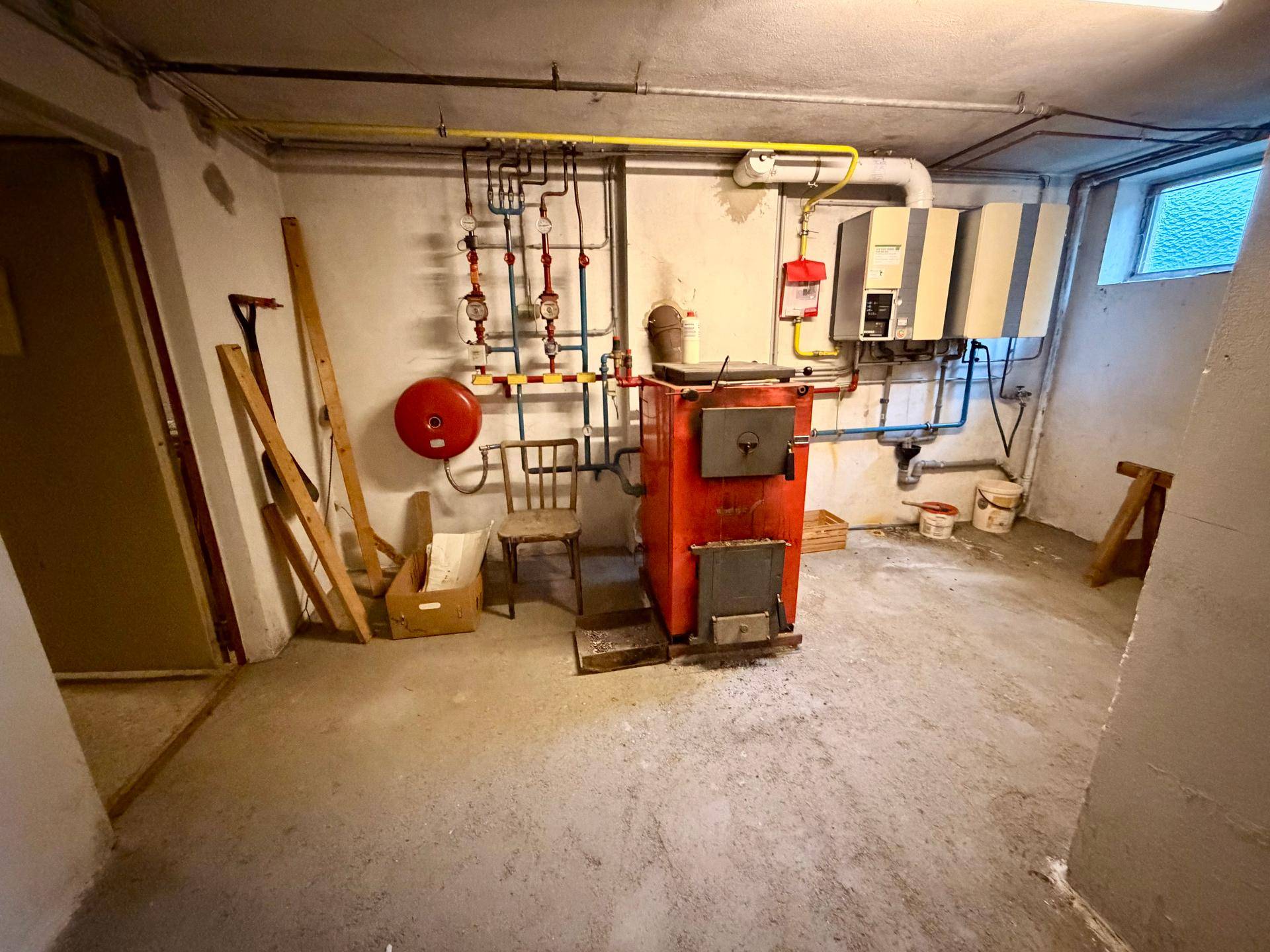 Heizungsraum im Keller mit altem Heizkessel und sichtbaren Rohrleitungen, bereit für Modernisierung.