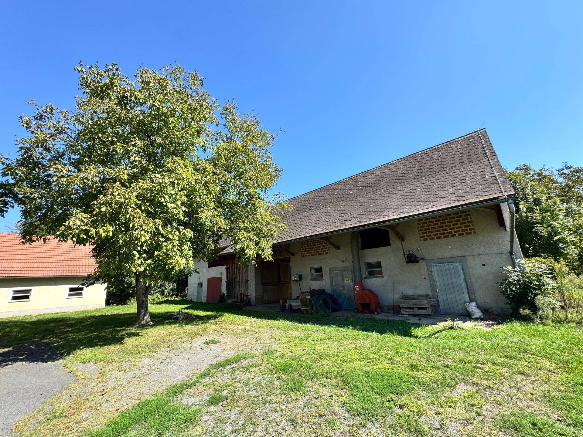 Historisches Bauernhaus mit Scheune und großem Grundstück, umgeben von Bäumen und Natur.