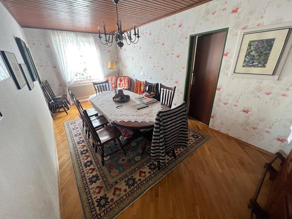 Esszimmer mit Holztisch, Stühlen, gemusterter Tapete und Holzboden.