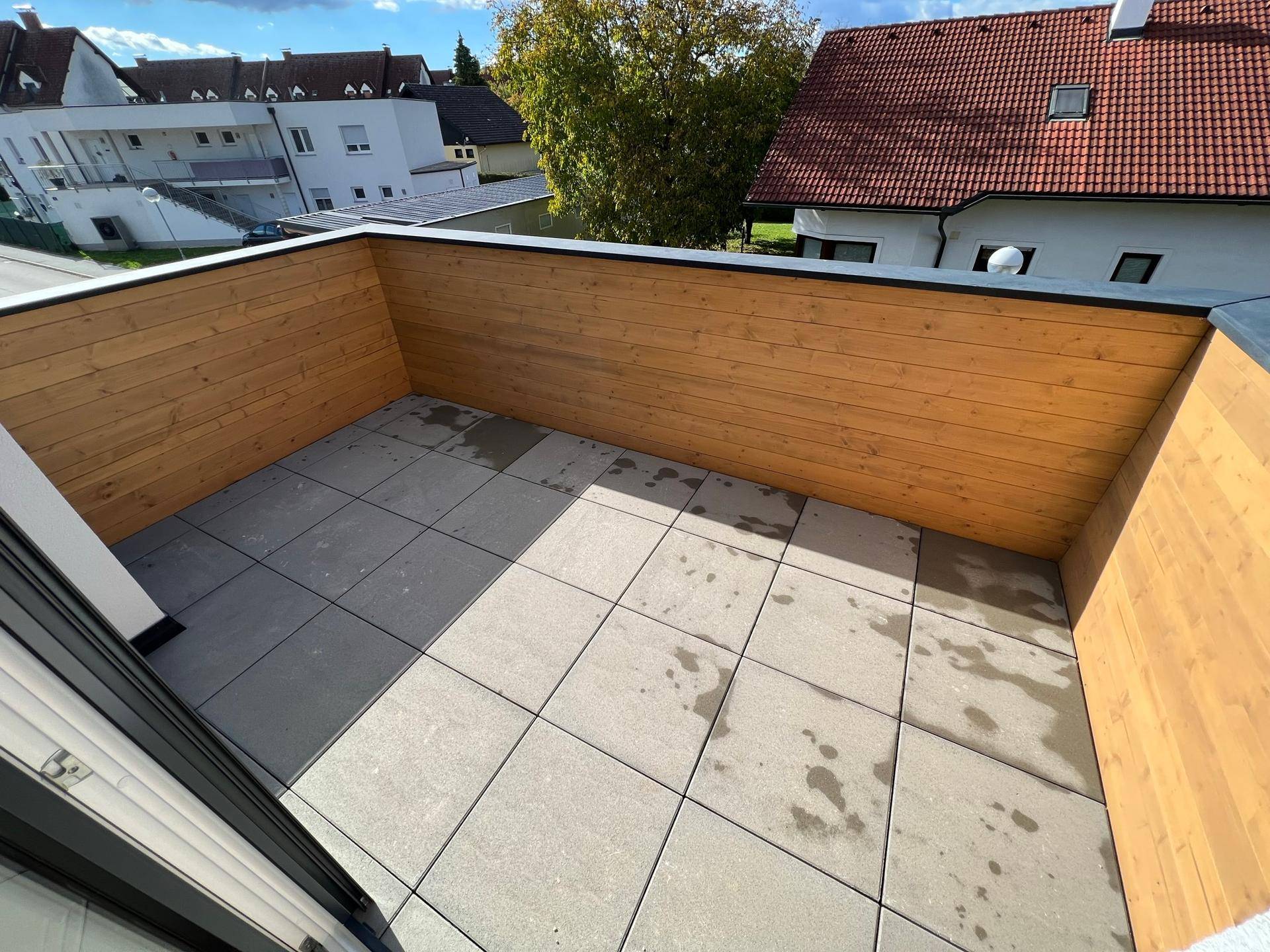 Geräumige Dachterrasse mit Fliesenboden und Holzwänden, ideal für Entspannung im Freien.