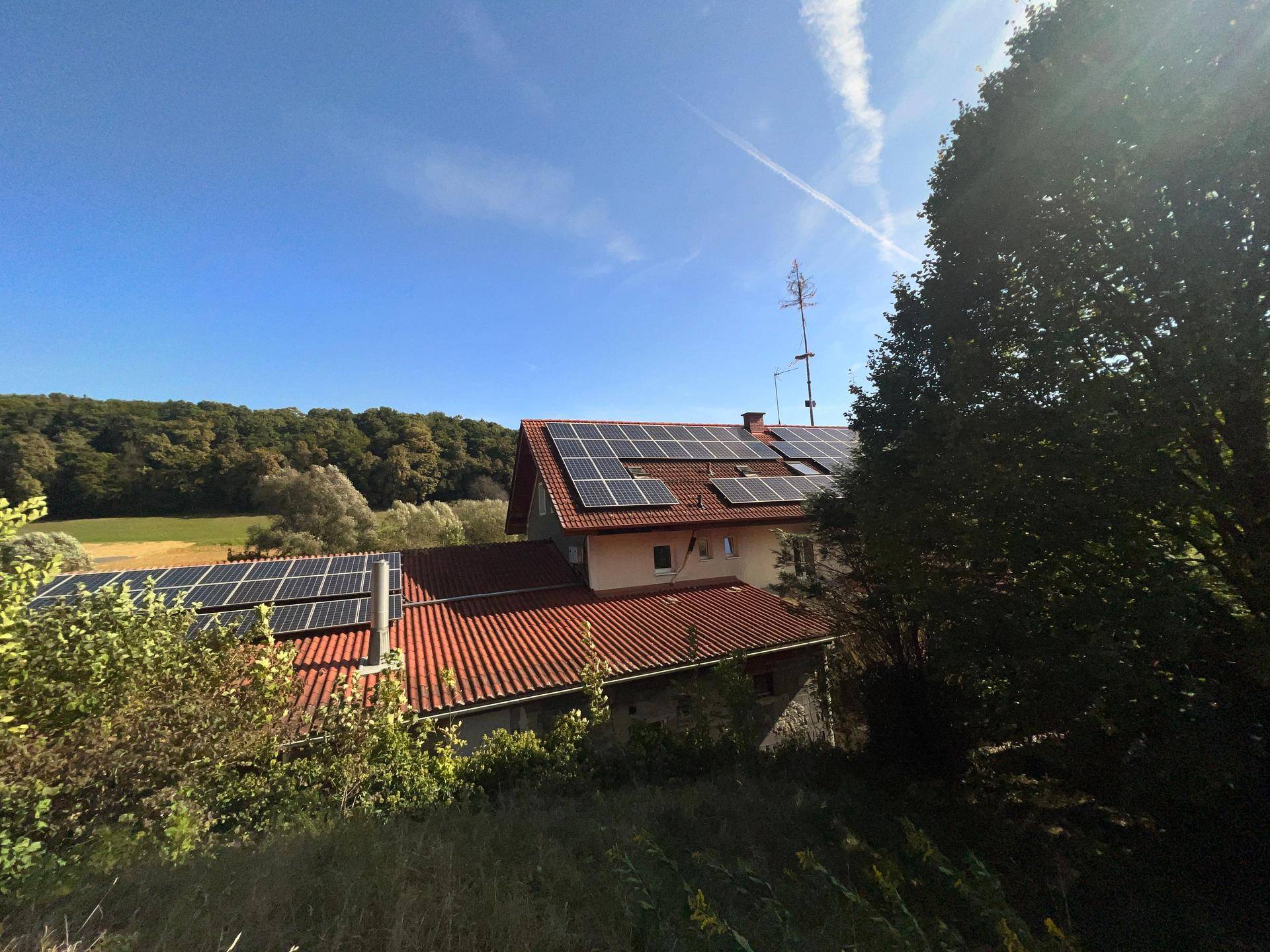 Dachansicht des Gebäudes mit zahlreichen Photovoltaik-Modulen und umgebender grüner Landschaft.