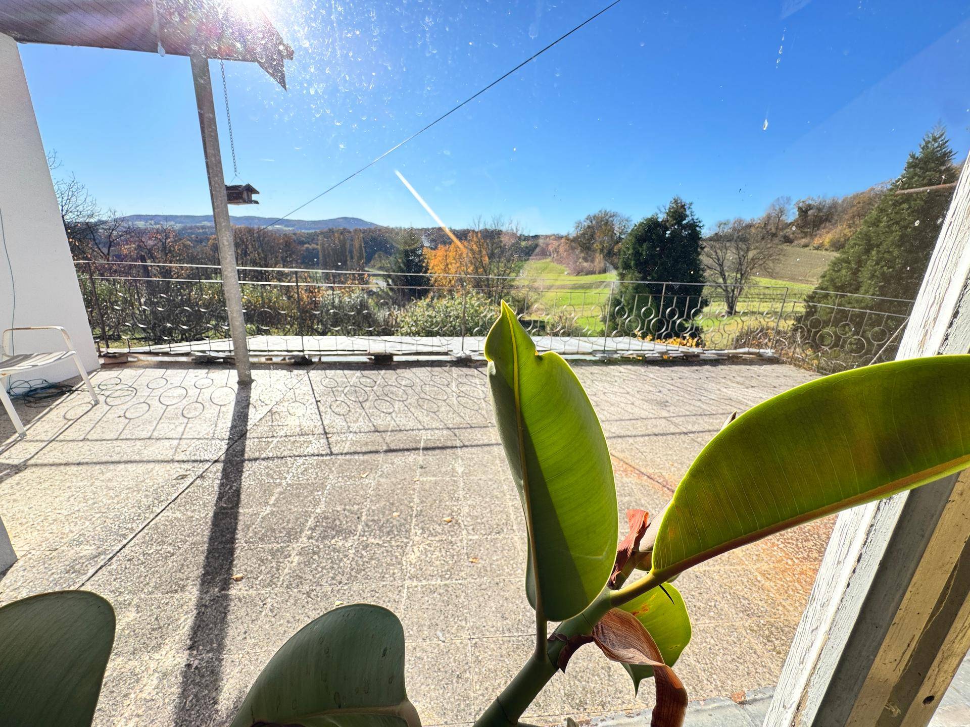Geräumige Terrasse mit Blick auf die grüne Landschaft unter strahlendem Sonnenschein.