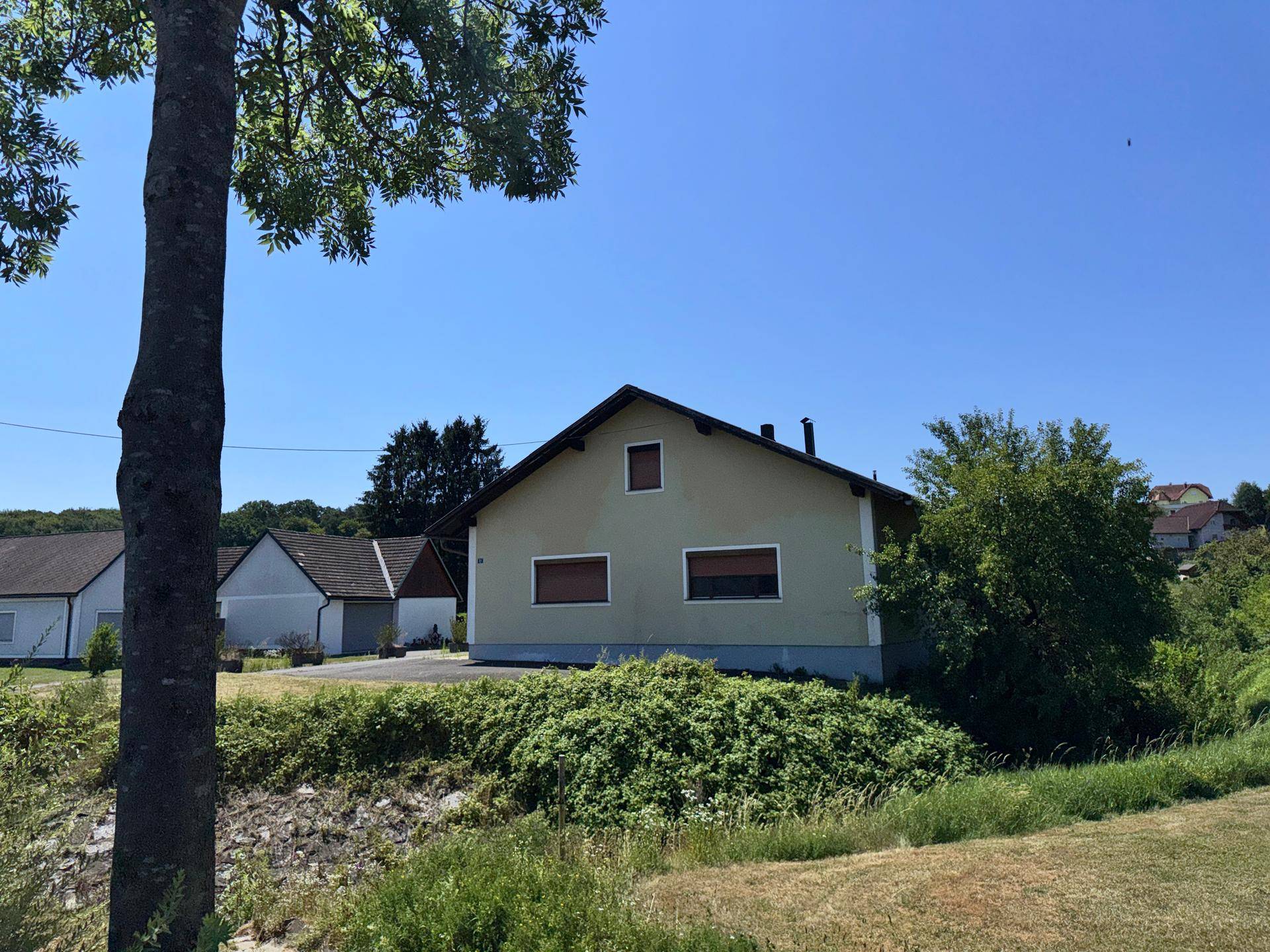 Rückansicht des Hauses mit grüner Umgebung und angrenzendem Bachlauf.