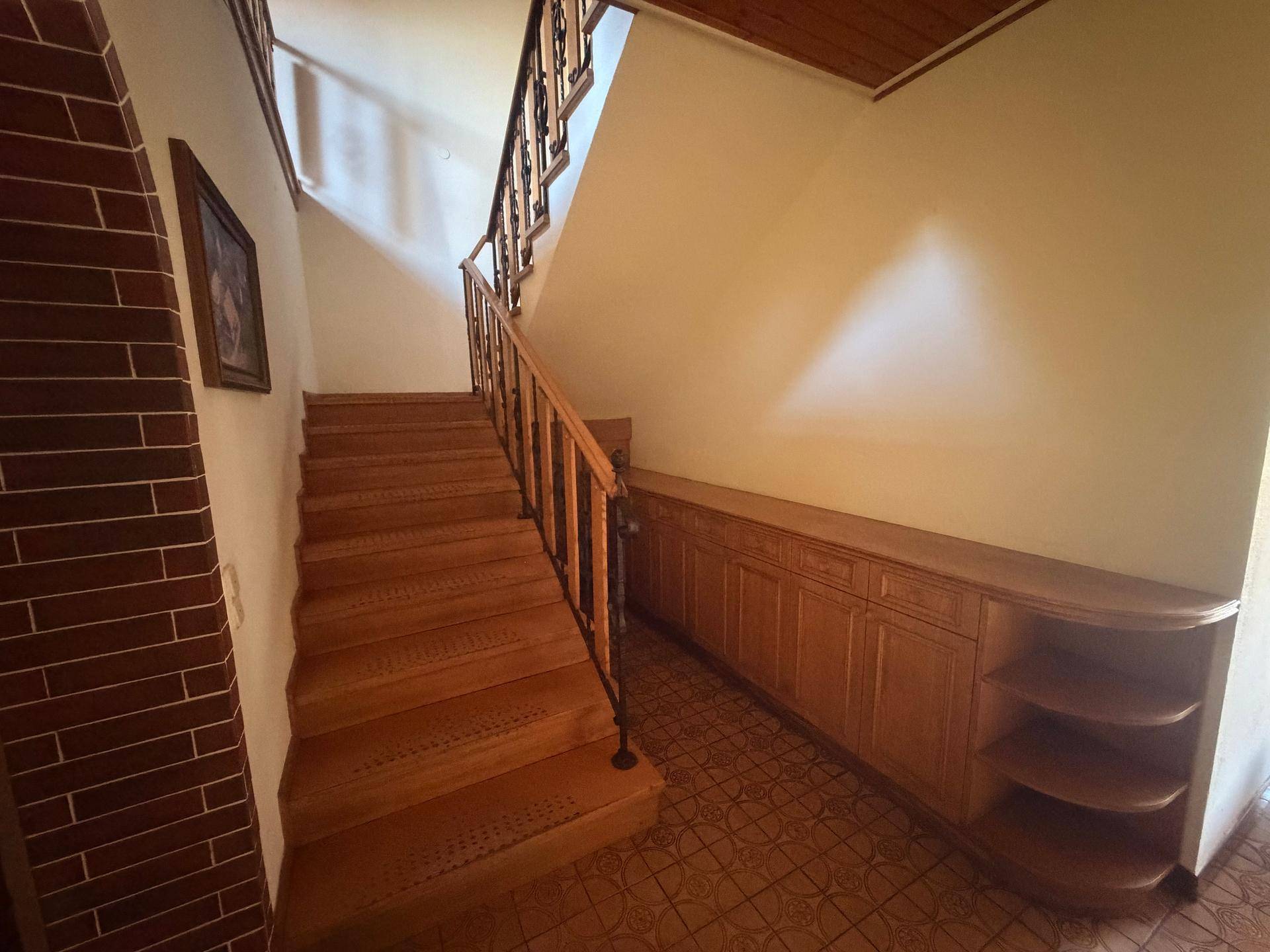 Geräumiger Flur mit Holztreppe, Einbauschränken und gemustertem Fliesenboden.