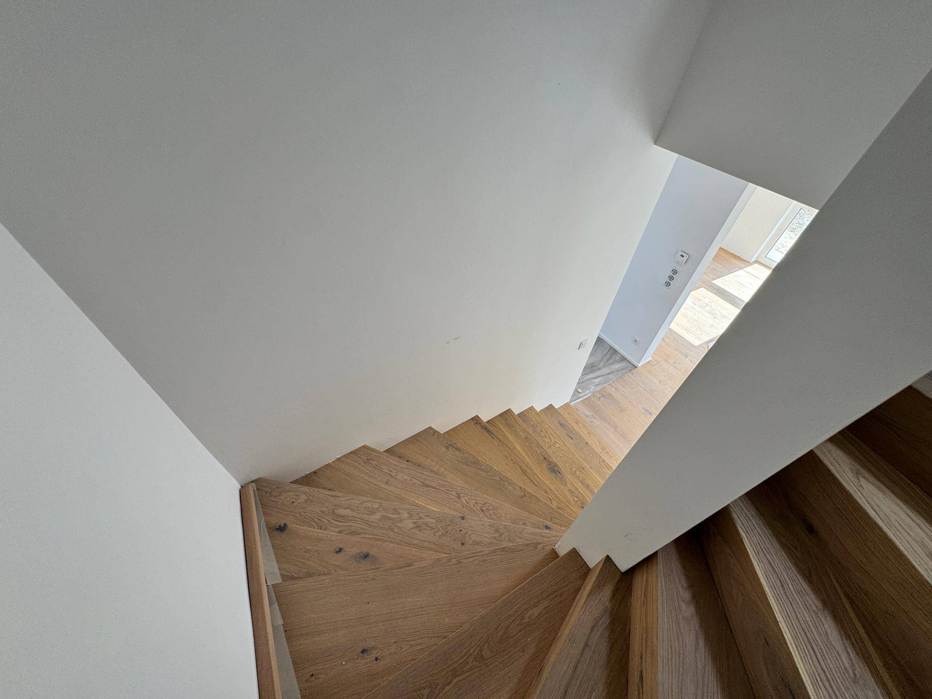 Elegante Holztreppe von oben gesehen, die die verschiedenen Ebenen des Hauses verbindet.