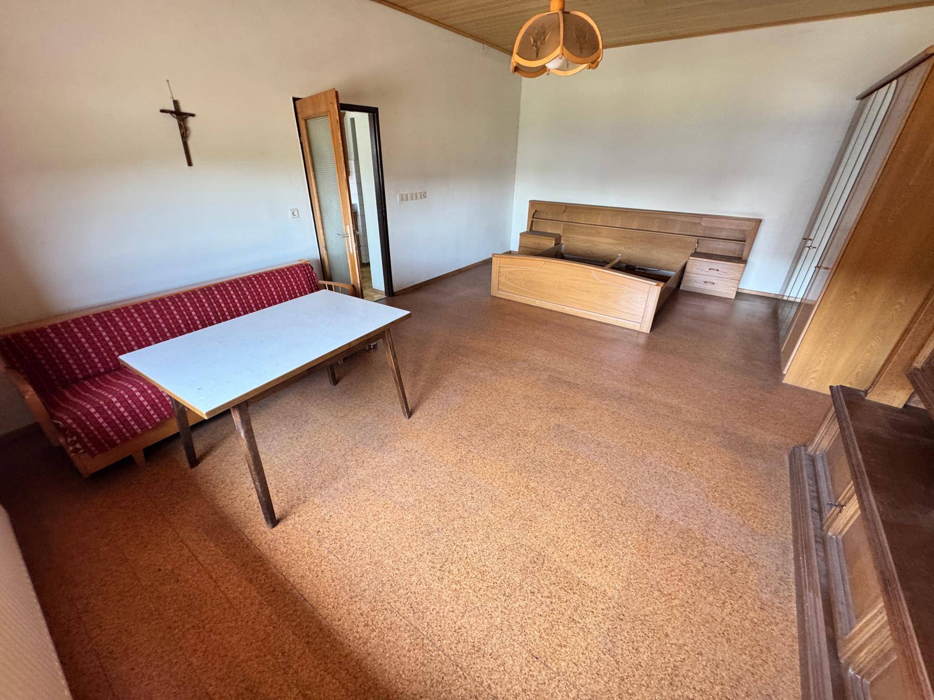Geräumiges Schlafzimmer mit Holzdecke, Bettrahmen und einfacher Einrichtung.