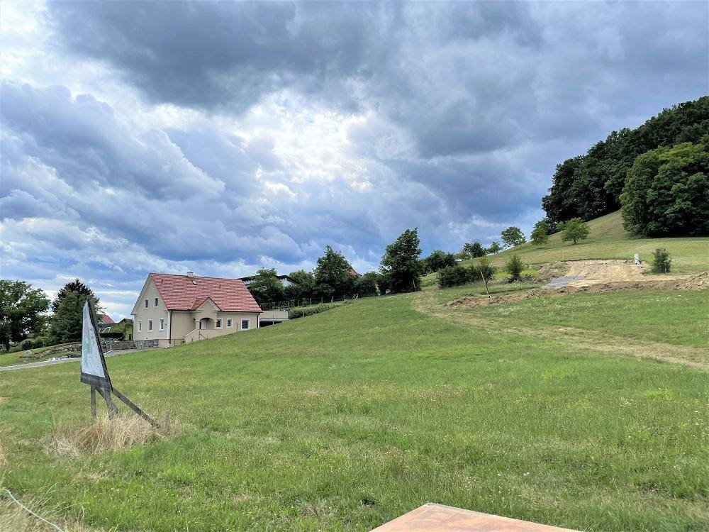 Grüne Hügellandschaft mit einem traditionellen Haus unter einem bewölkten Himmel.