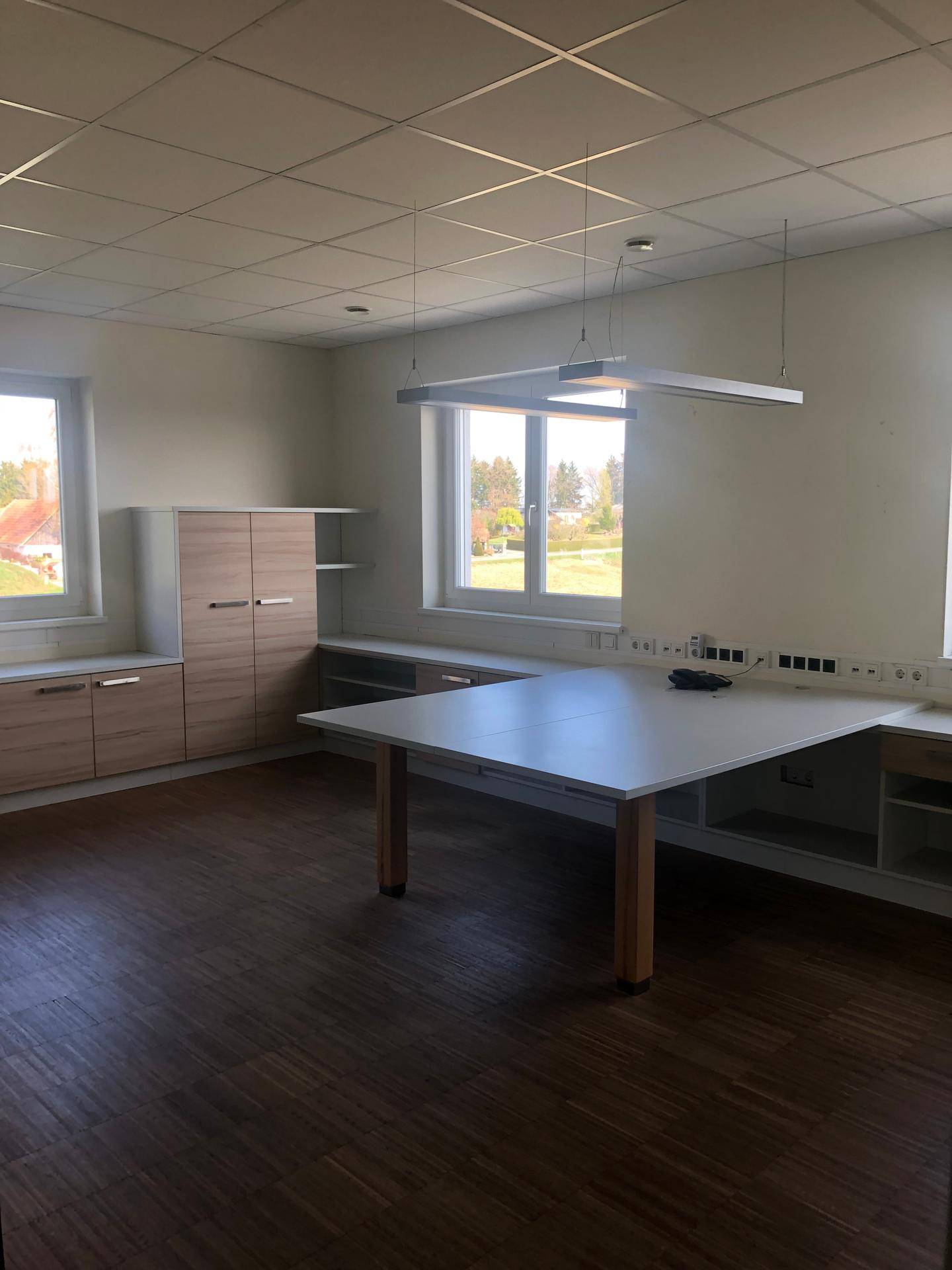 Geräumiges Büro mit Laminatboden, großen Fenstern und Einbauschränken.