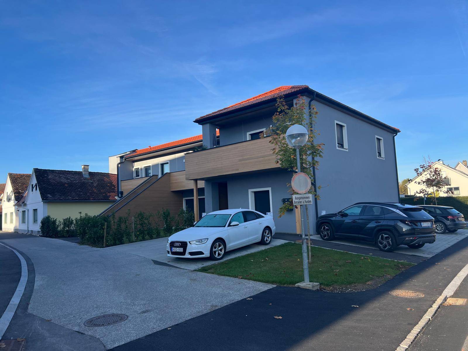 Ansicht des modernen Gebäudes von der Straße mit Parkplätzen und blauer Himmel.