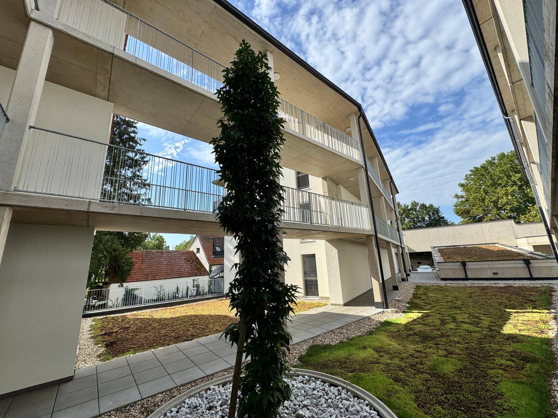 Blick auf die moderne Architektur des Neubaus mit begrüntem Innenhof und Balkonen.
