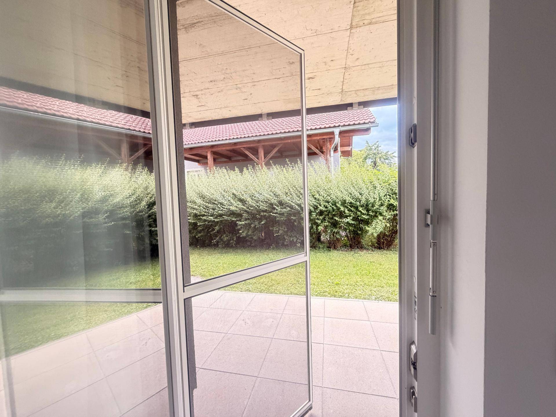 Blick durch eine Terrassentür auf den grünen Gartenbereich.