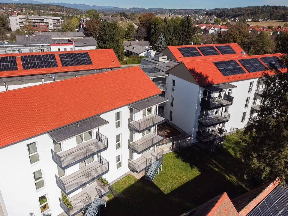 Luftaufnahme von modernen Wohngebäuden mit roten Dächern und Photovoltaikanlagen.