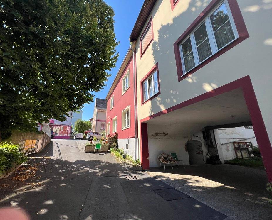 Überdachter Parkbereich und ein schmaler Weg, der bergauf zu weiteren Gebäuden führt.