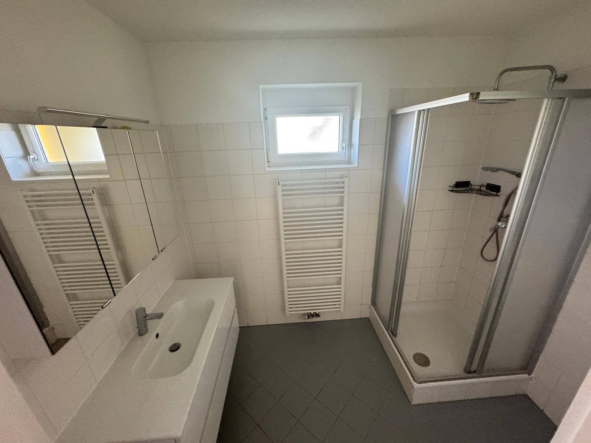 Modernes Badezimmer mit Dusche, Waschbeckenunterschrank, Spiegel und beheiztem Handtuchhalter.